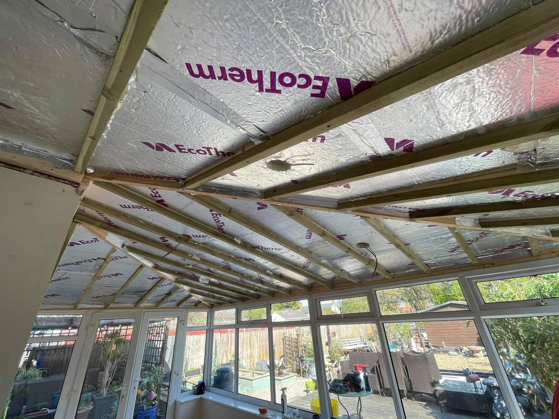 Conservatory roof interior showing timber frame with foil-backed insulation between rafters