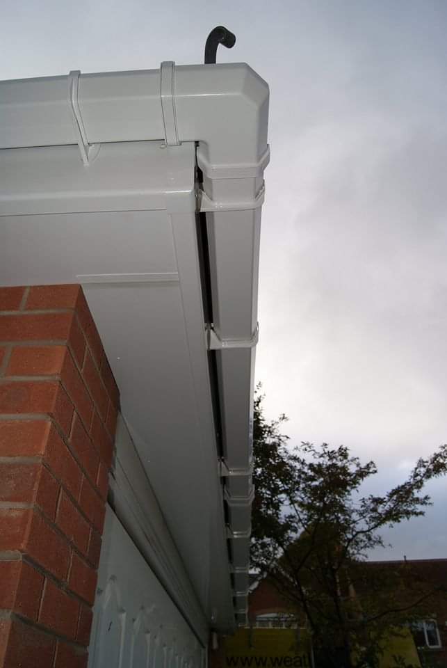 White uPVC fascias, soffits and square guttering with downpipe on brick house