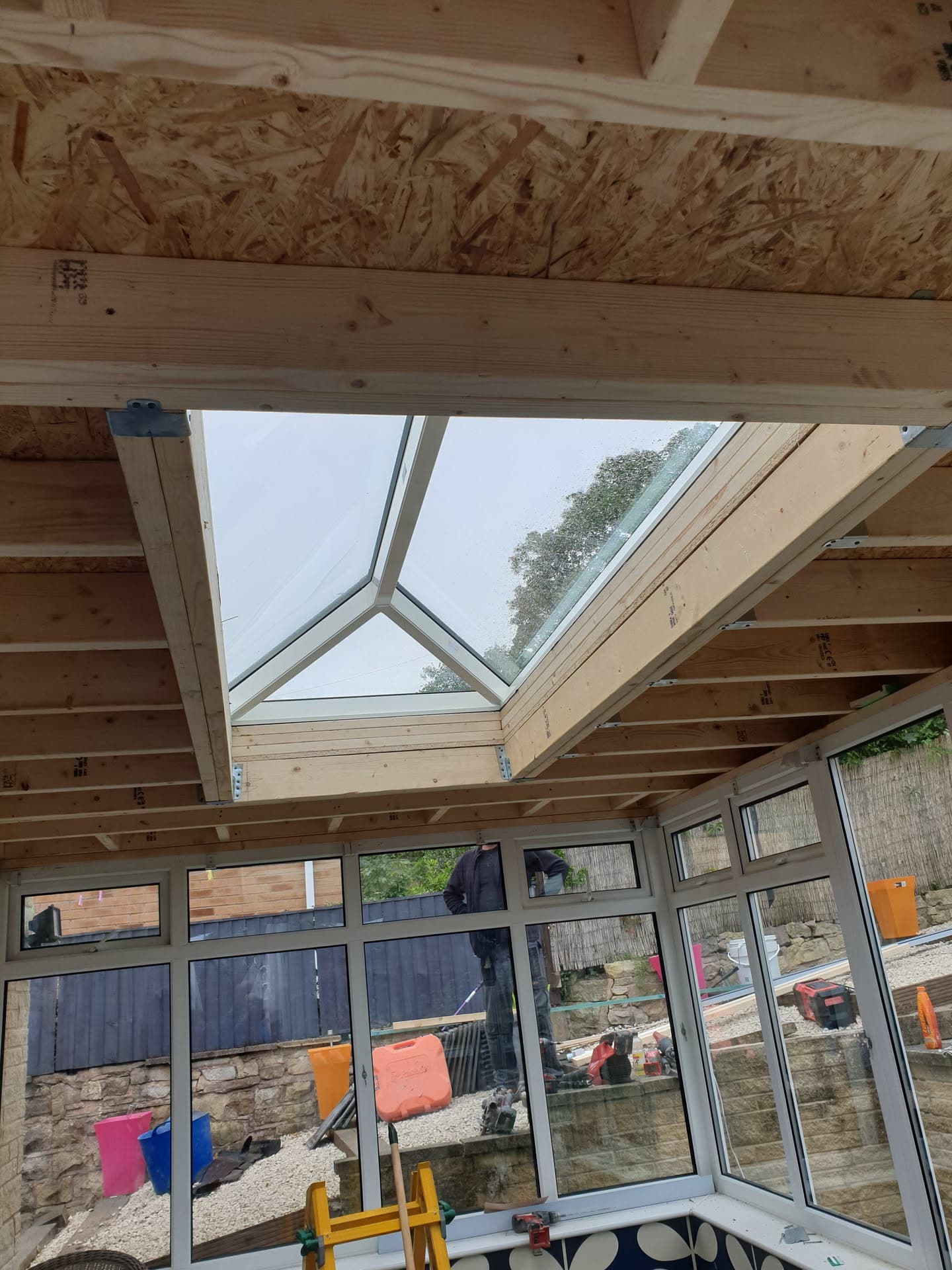 Interior view of conservatory roof with glass lantern skylight and exposed timber frame during construction