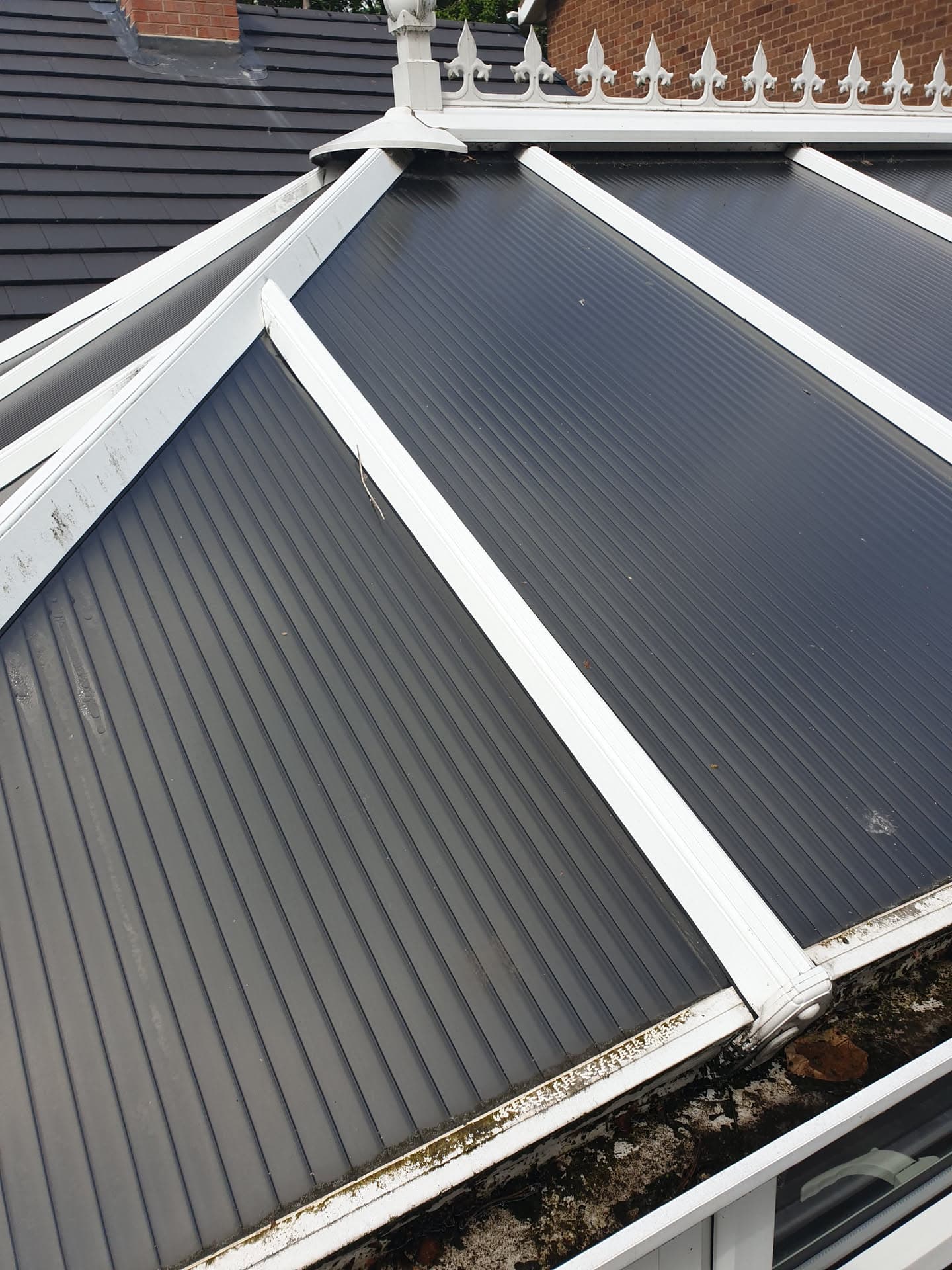 Grey conservatory roof with white uPVC frames and decorative ridge cresting