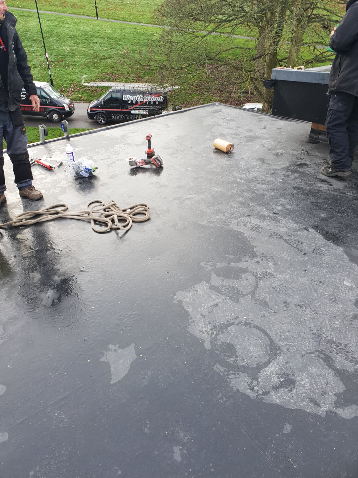 Flat roof installation in progress with grey felt surface and tools