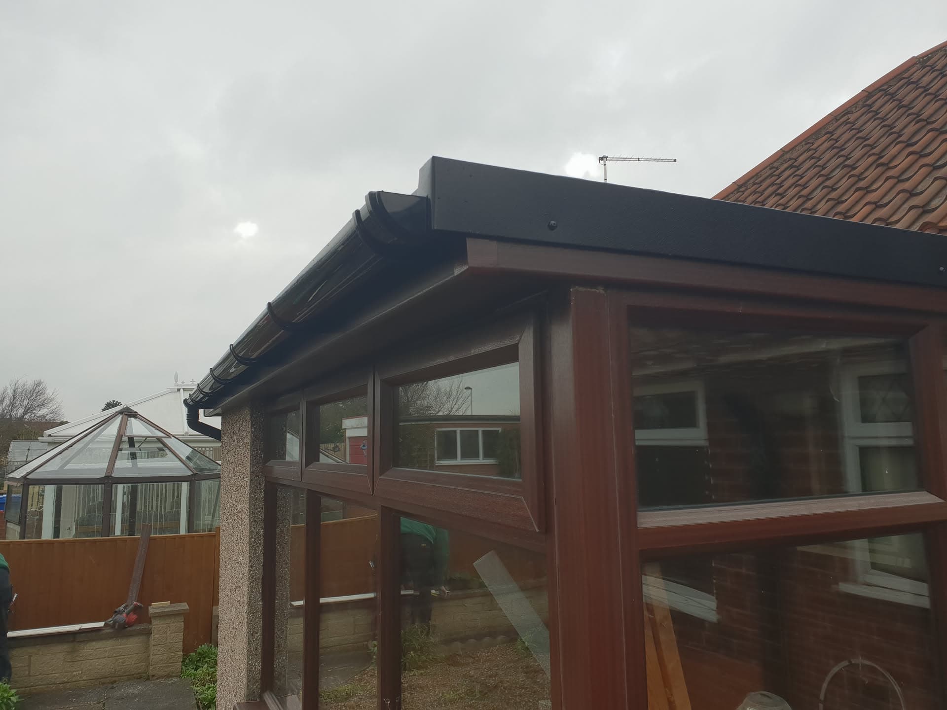 Conservatory with dark grey flat roof, brown uPVC frames and fascias
