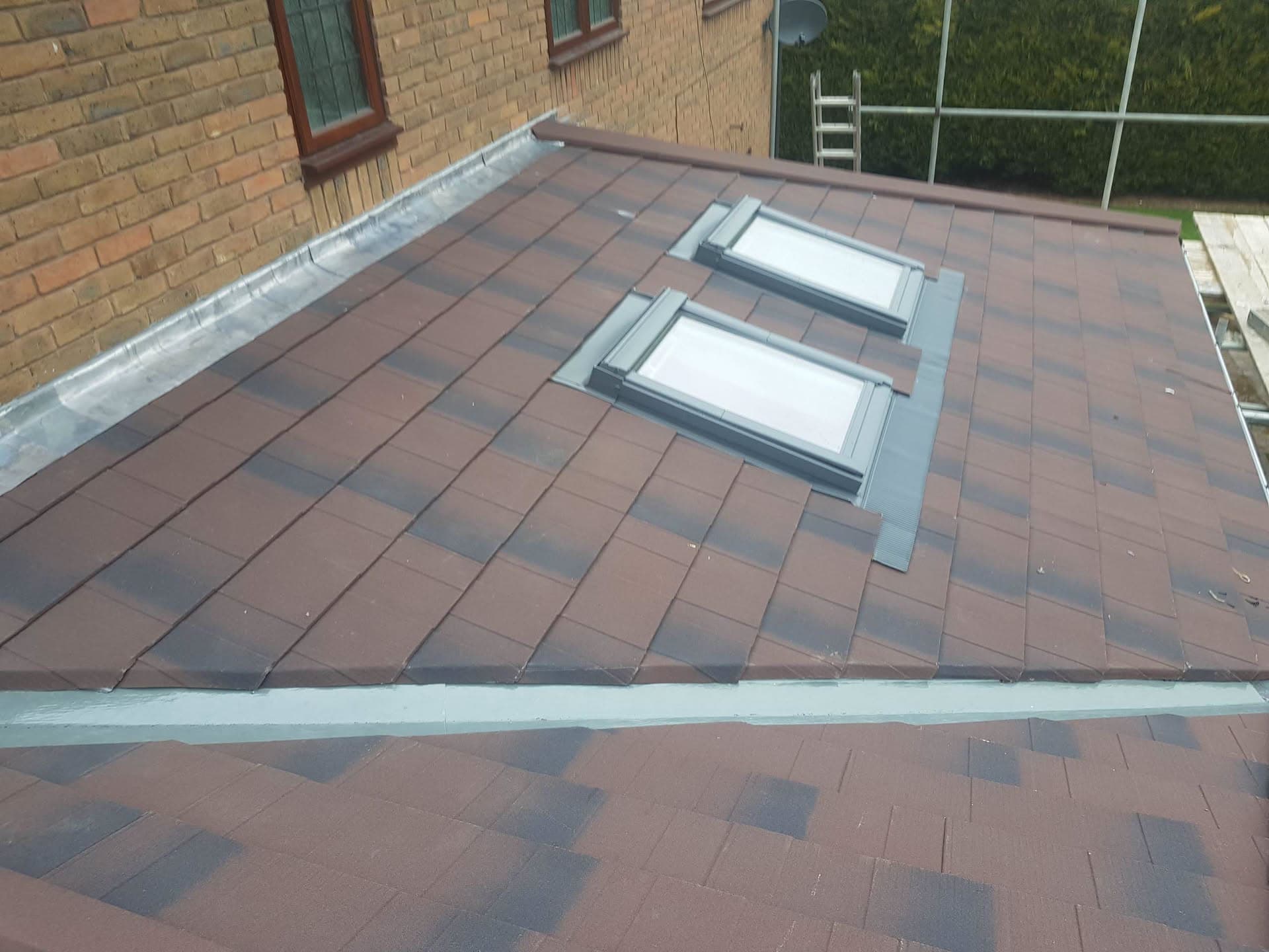 Flat roof with brown and grey concrete tiles and two roof windows