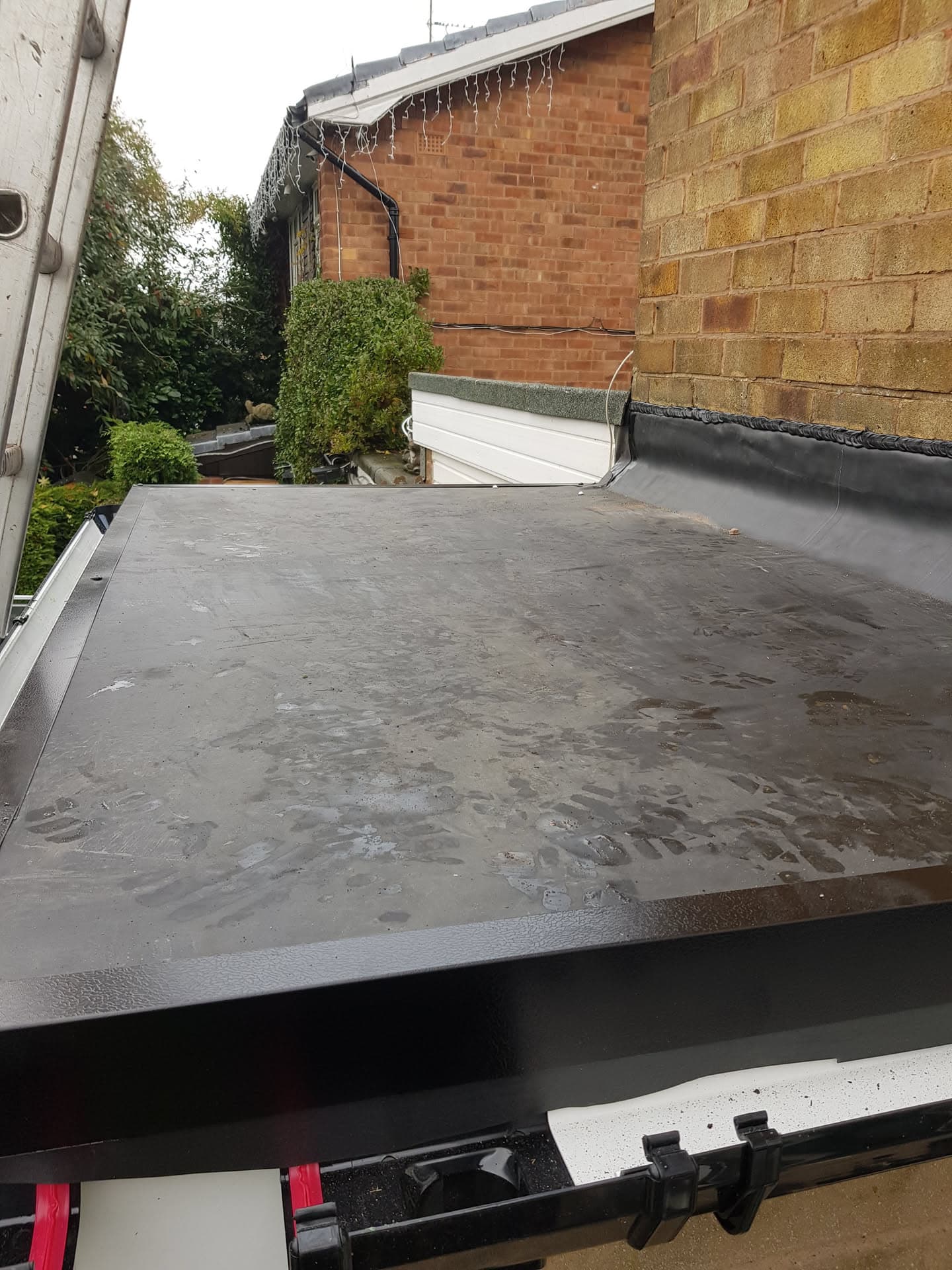Flat roof with grey EPDM rubber membrane and white fascia trim
