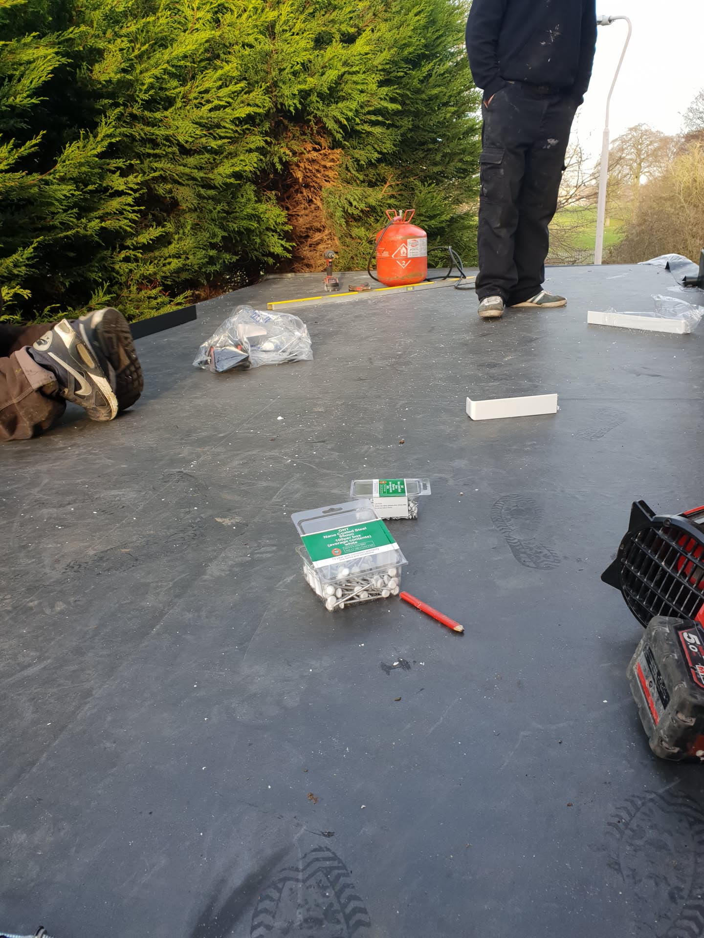 Fitter working on flat roof with EPDM rubber membrane and installation materials