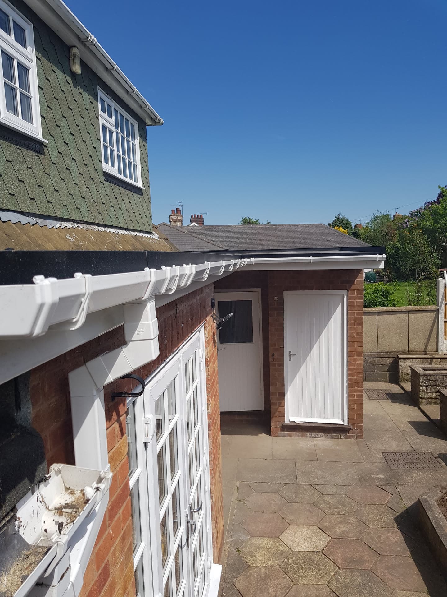 White fascias, soffits and guttering on flat-roofed extension with brick walls