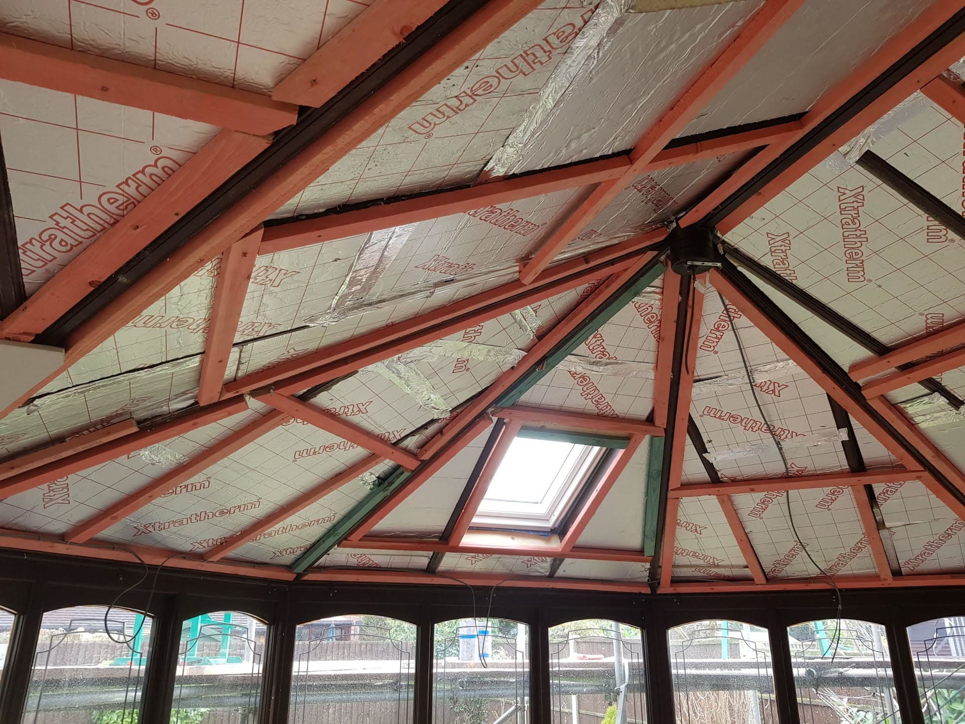 Interior view of pitched conservatory roof with exposed timber rafters and insulation boards fitted between beams