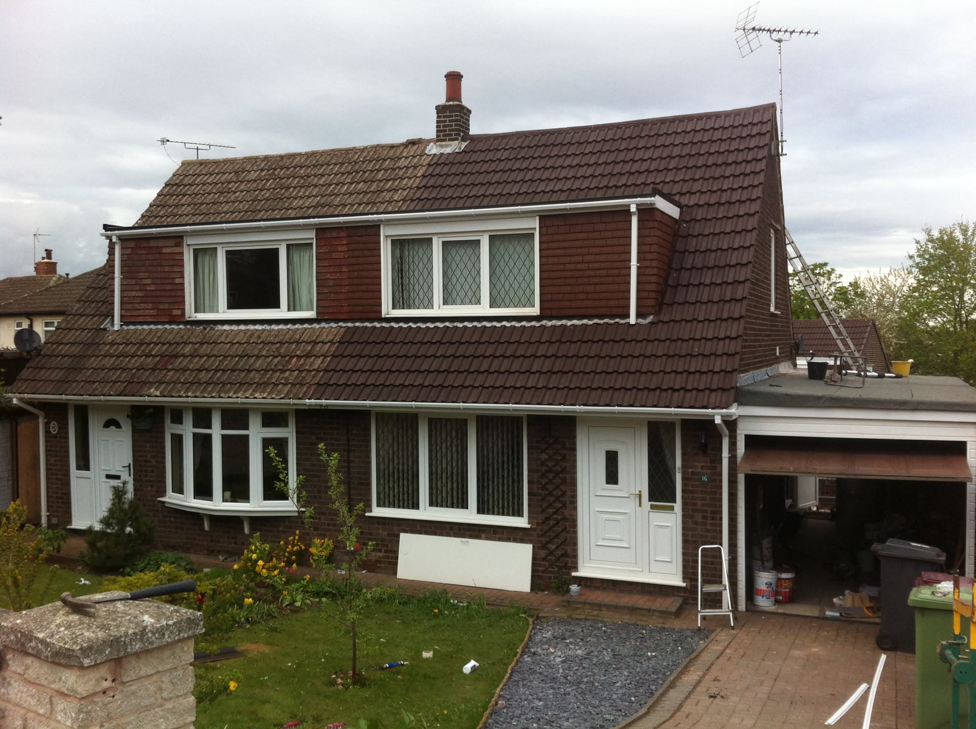 Brown concrete tiled pitched roof on two-storey house with dormer window and chimney