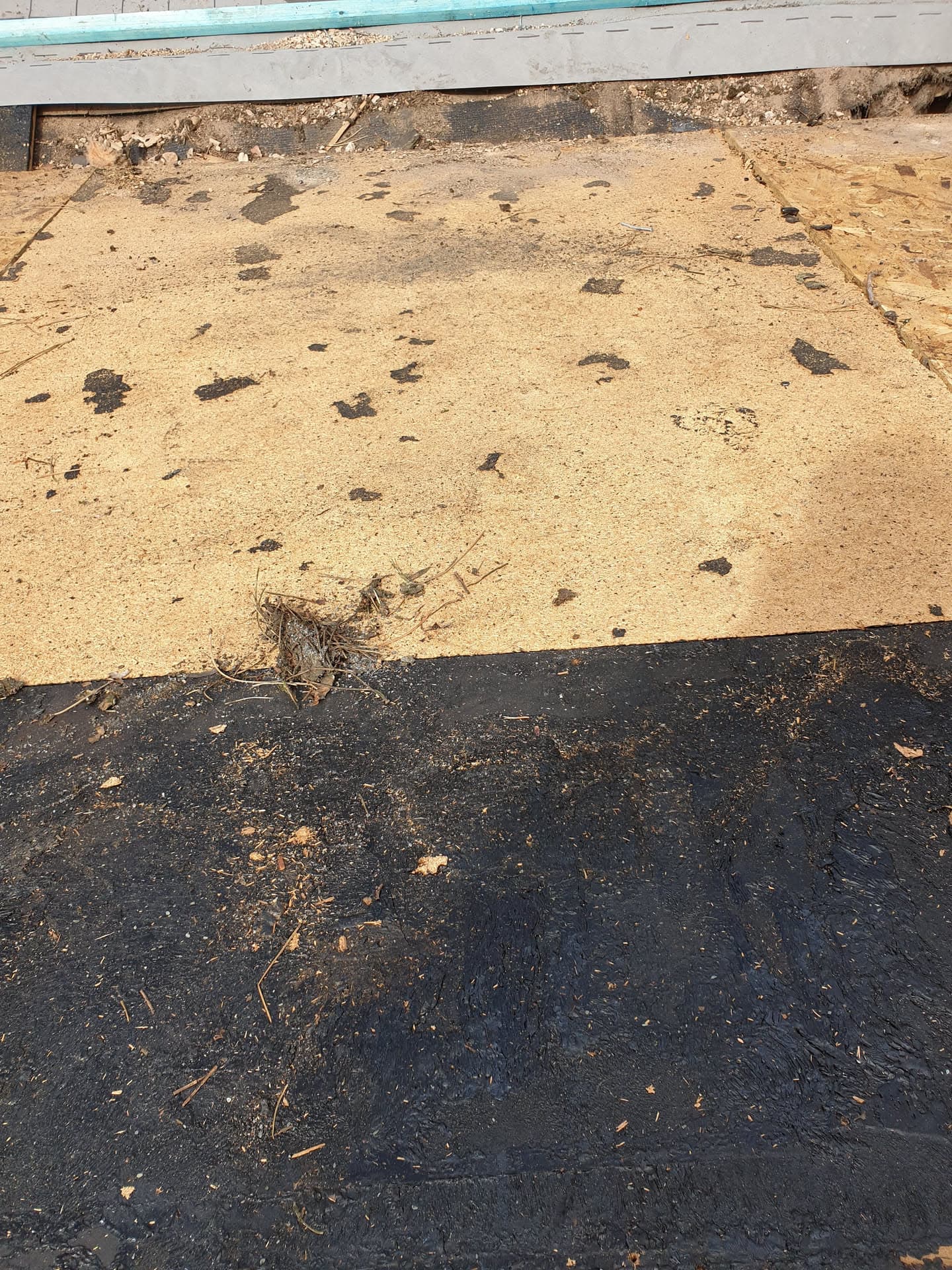 Flat roof surface showing old felt roofing with debris and wear