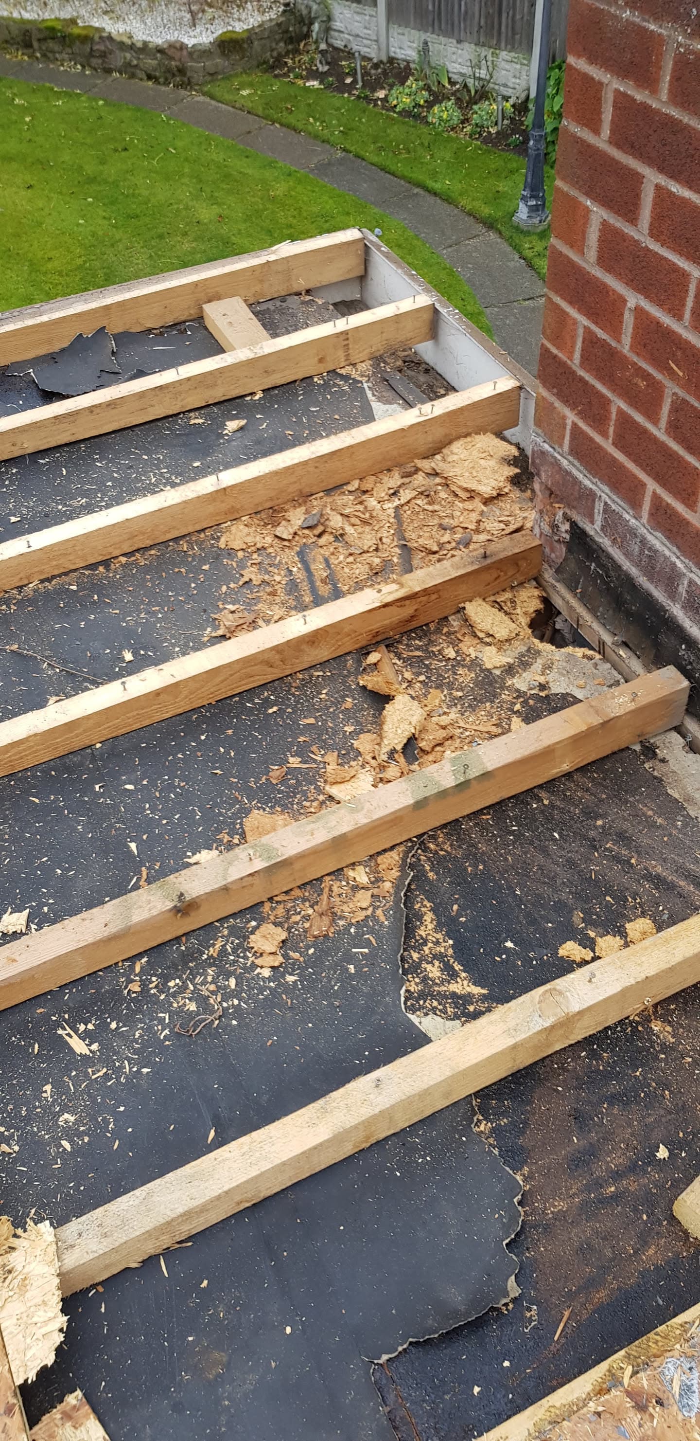 Flat roof with timber battens and damaged felt surface showing deterioration