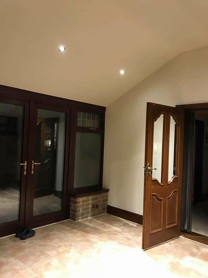 Interior view of conservatory with cream ceiling, recessed lighting and dark wood doors
