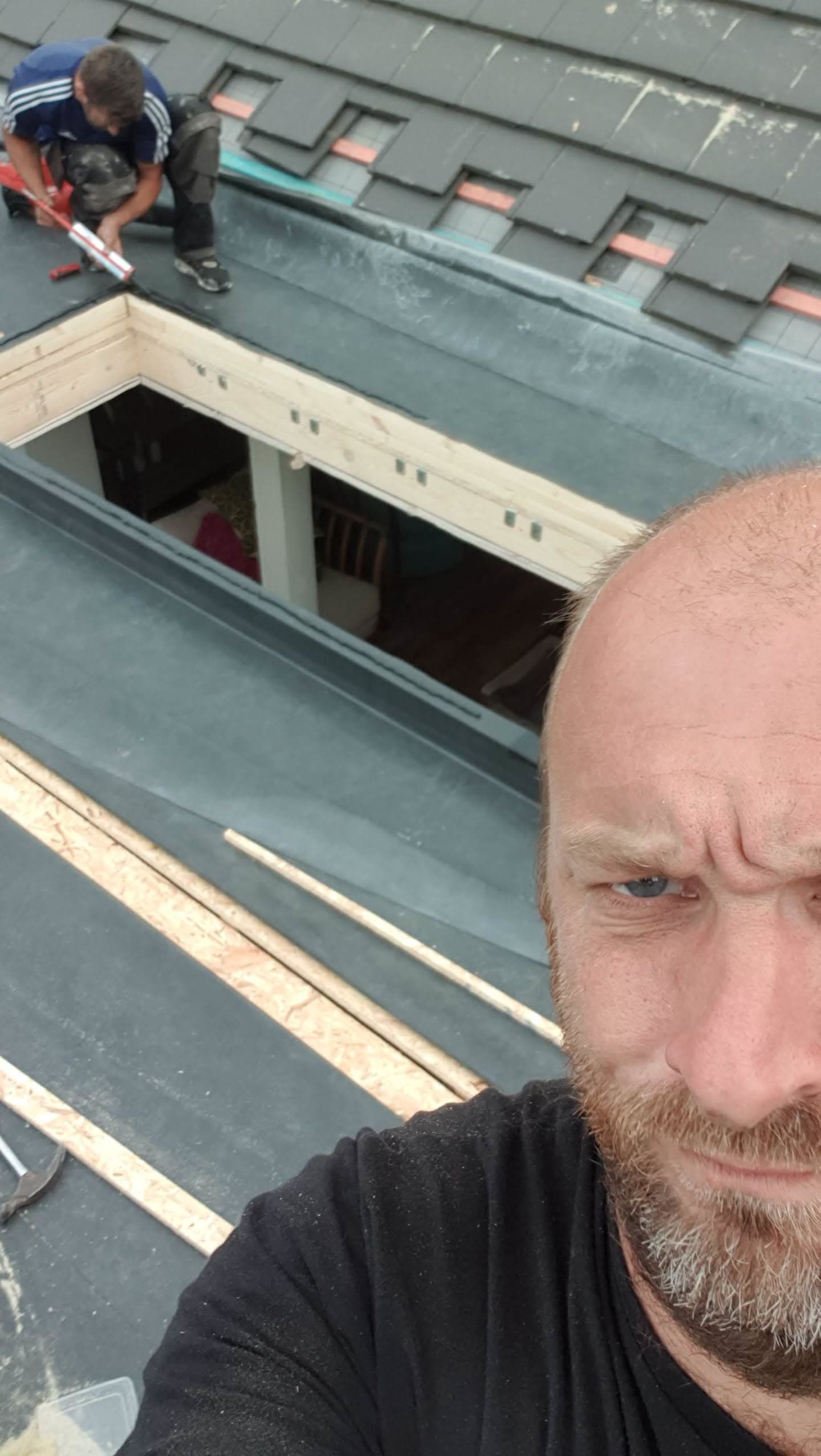 Fitters installing dormer window with grey slate roof and lead flashing