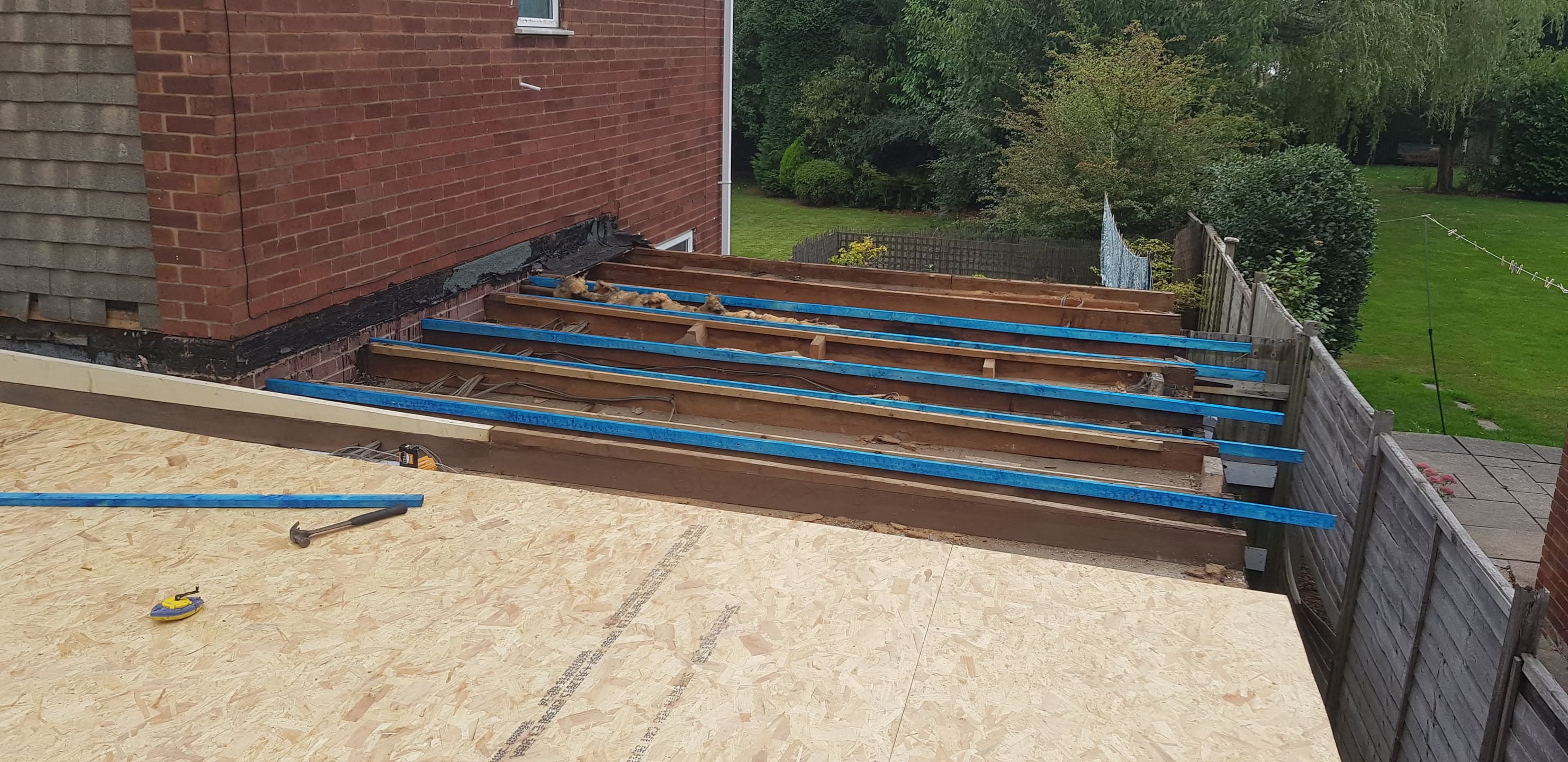 Flat roof construction in progress with timber joists and blue insulation boards