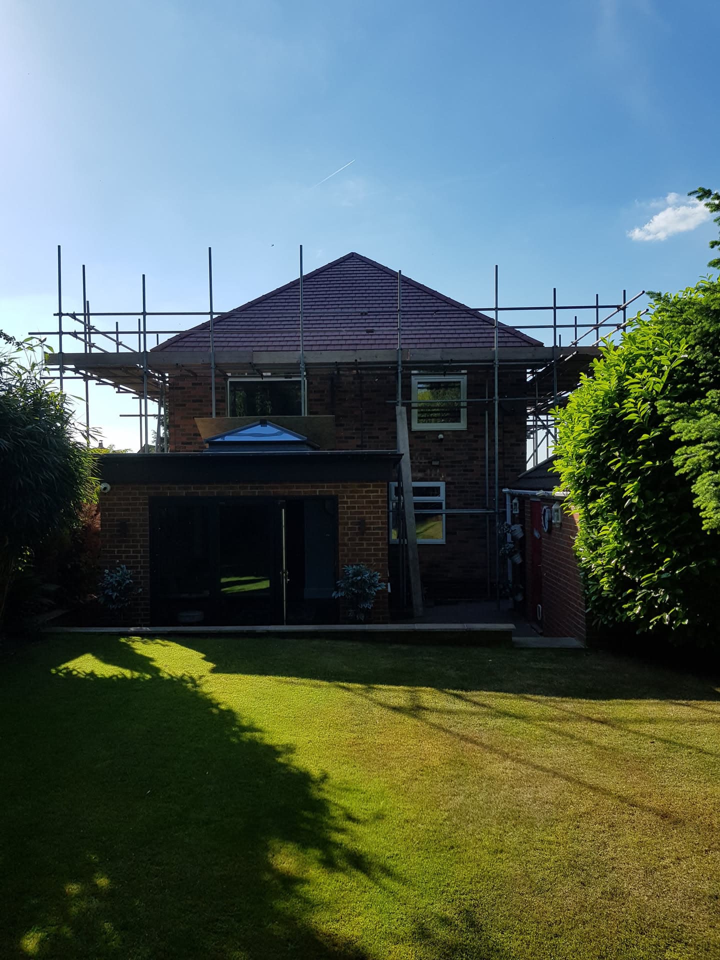 Pitched roof with dark concrete tiles and scaffolding erected around residential property
