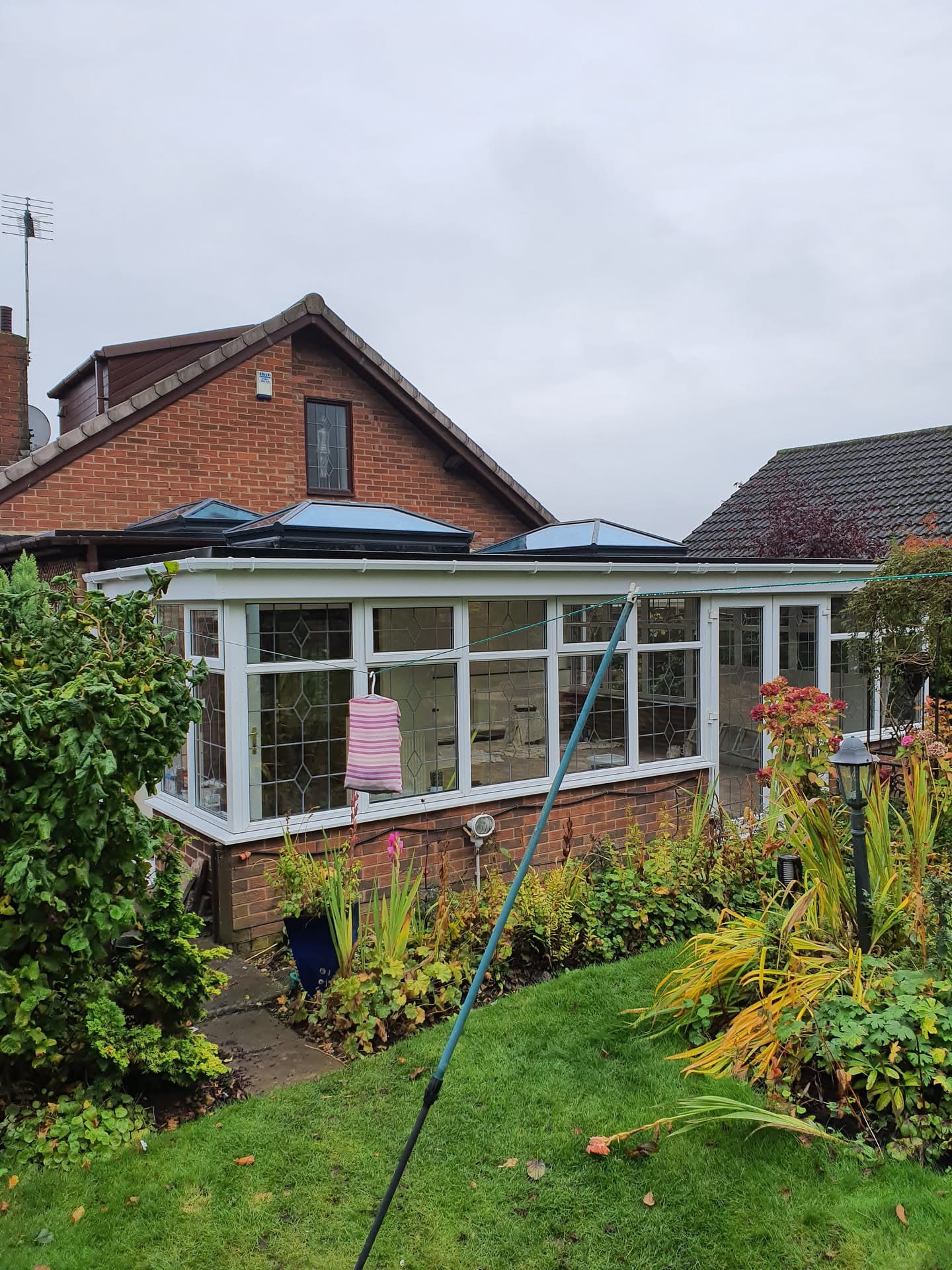 Conservatory with anthracite metal roof and white uPVC frames on brick house