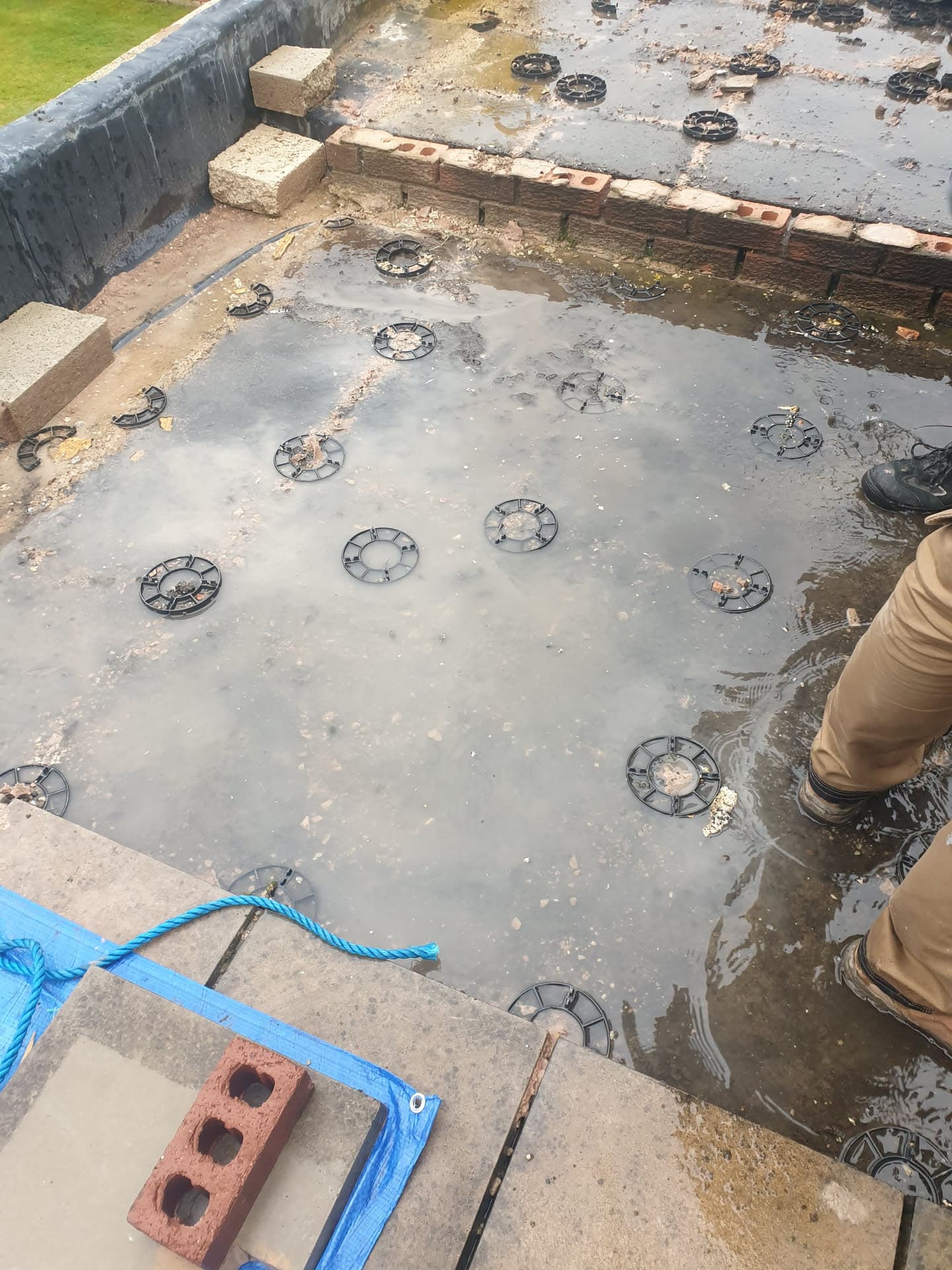 Flat roof installation in progress with support pads positioned on grey membrane surface