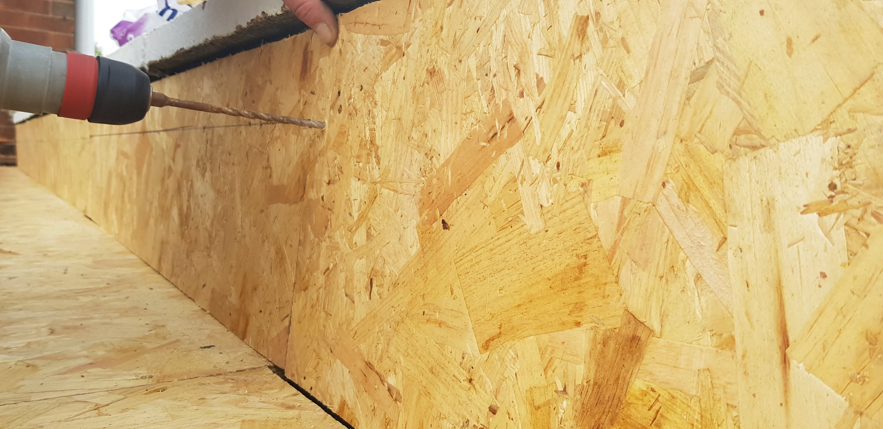 Fitter drilling screws into OSB board on flat roof deck