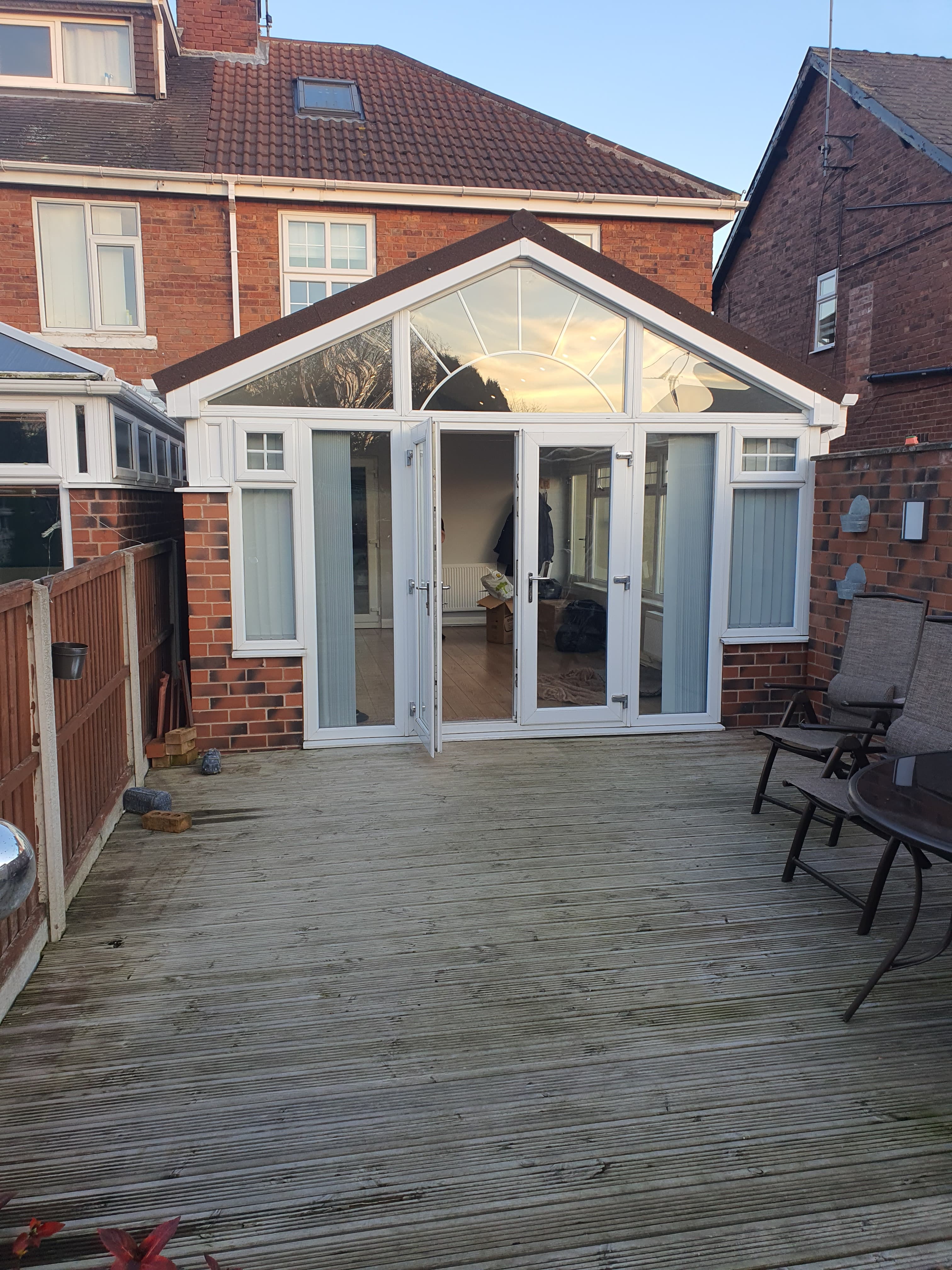 White uPVC conservatory with glazed gable roof and French doors on rear decking