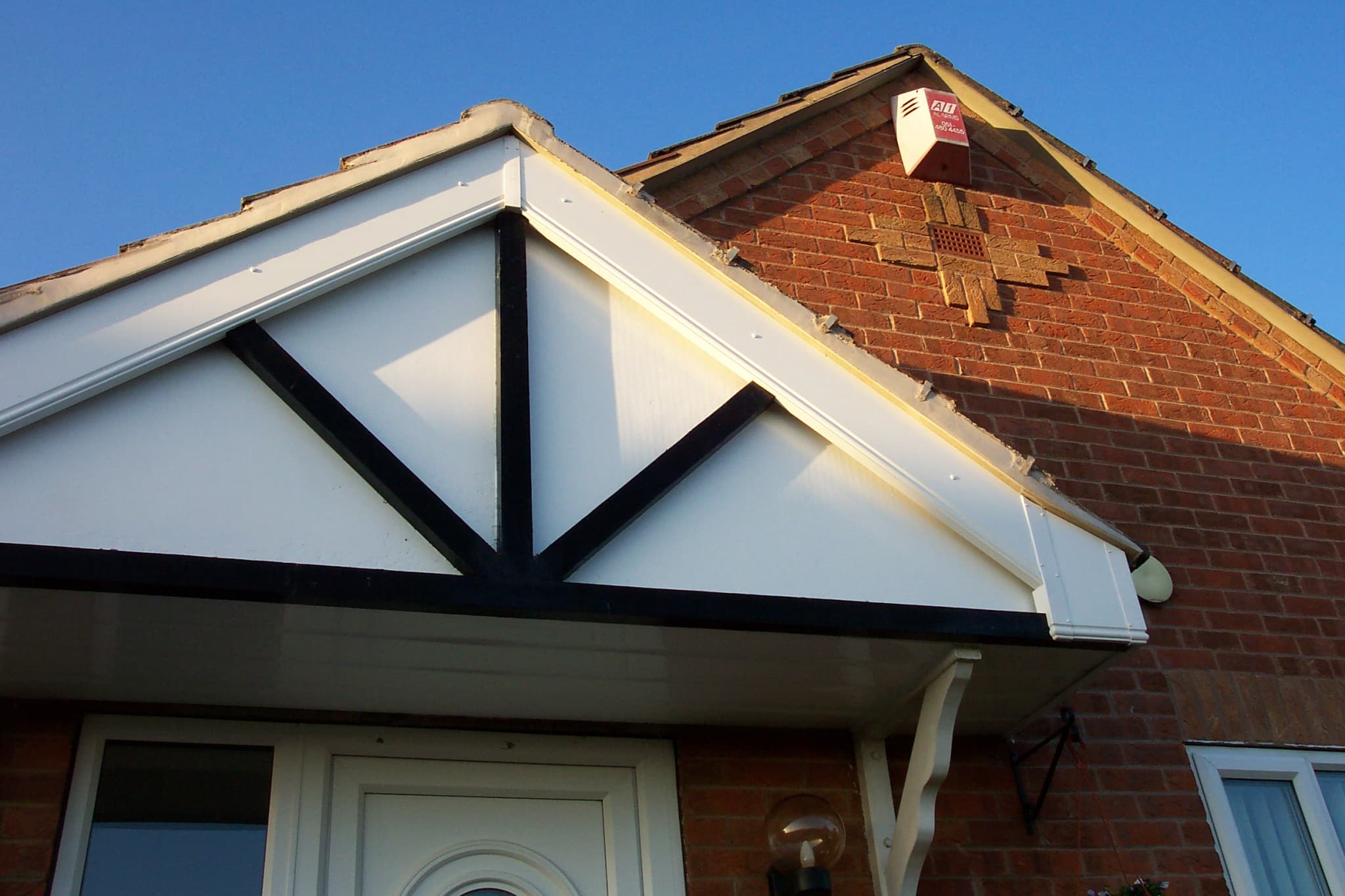 White fascias and soffits with decorative black timber detailing on brick house gable