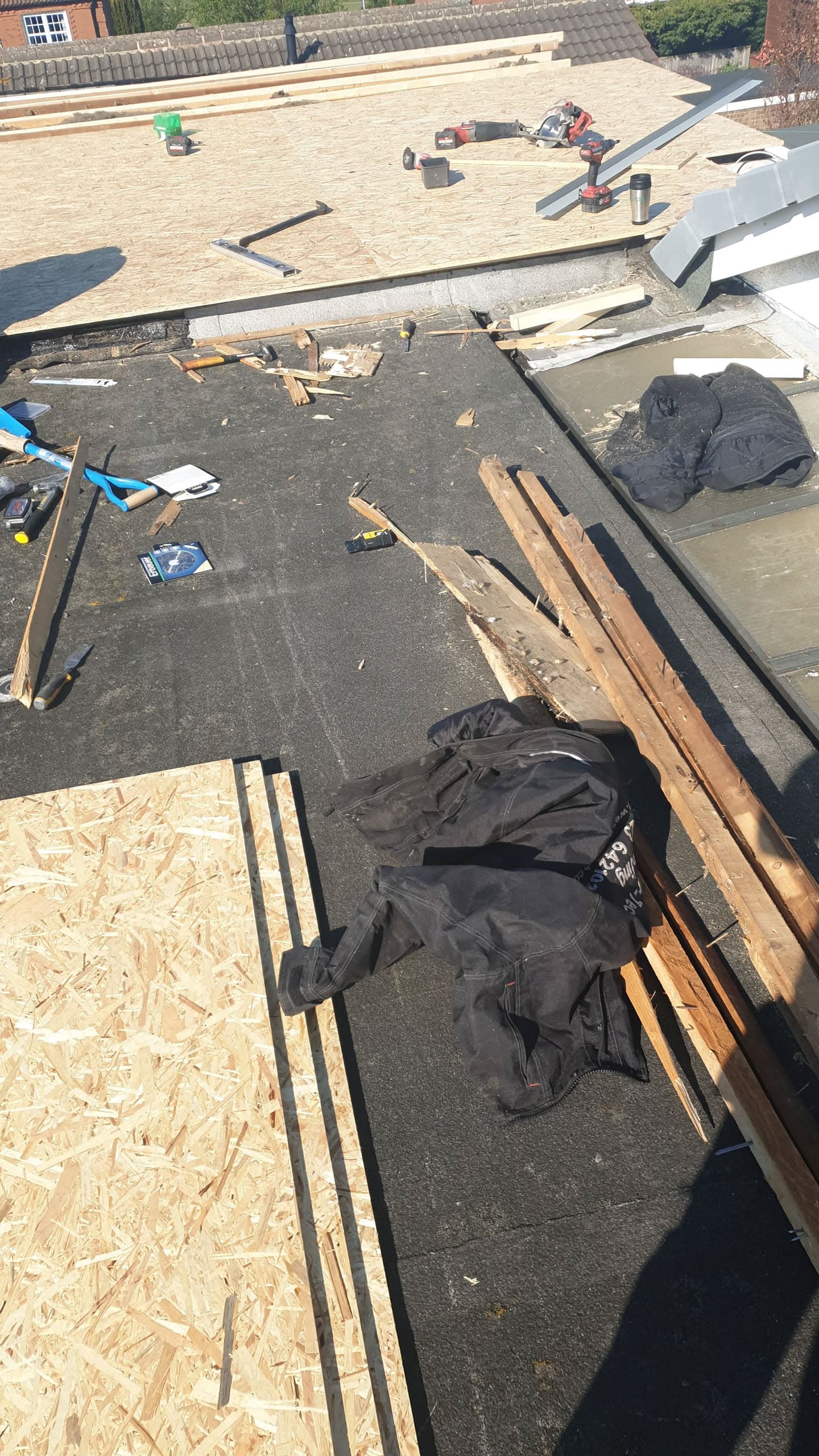 Flat roof renovation in progress with felt surface, timber joists and plywood boarding