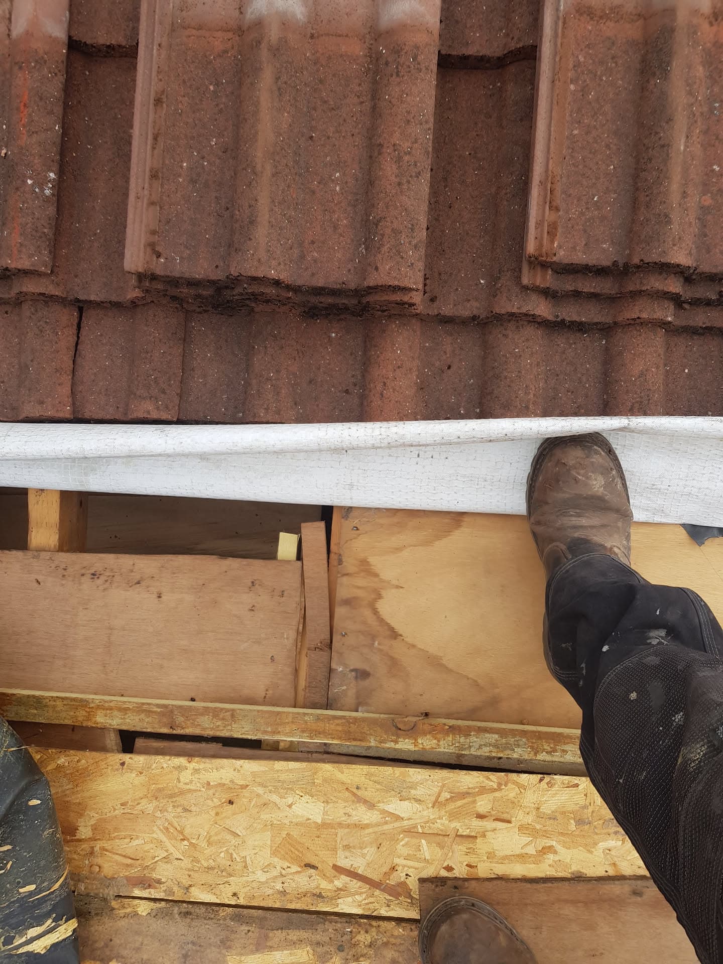 Fitter's view from roof edge showing brown concrete tiles and white fascia board