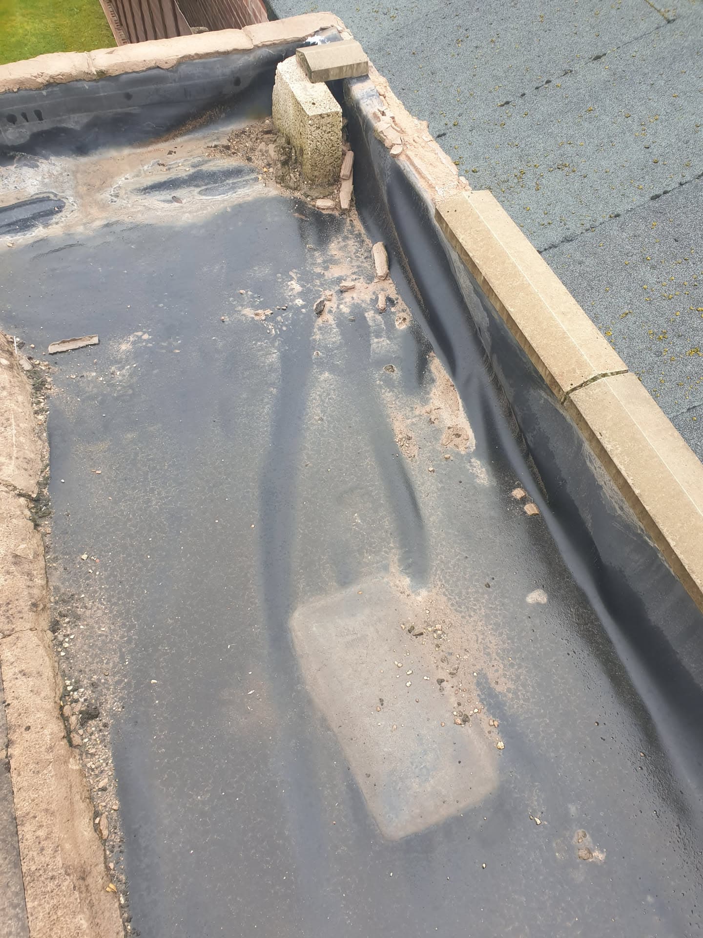 Flat roof with grey felt surface and lead flashing along parapet wall