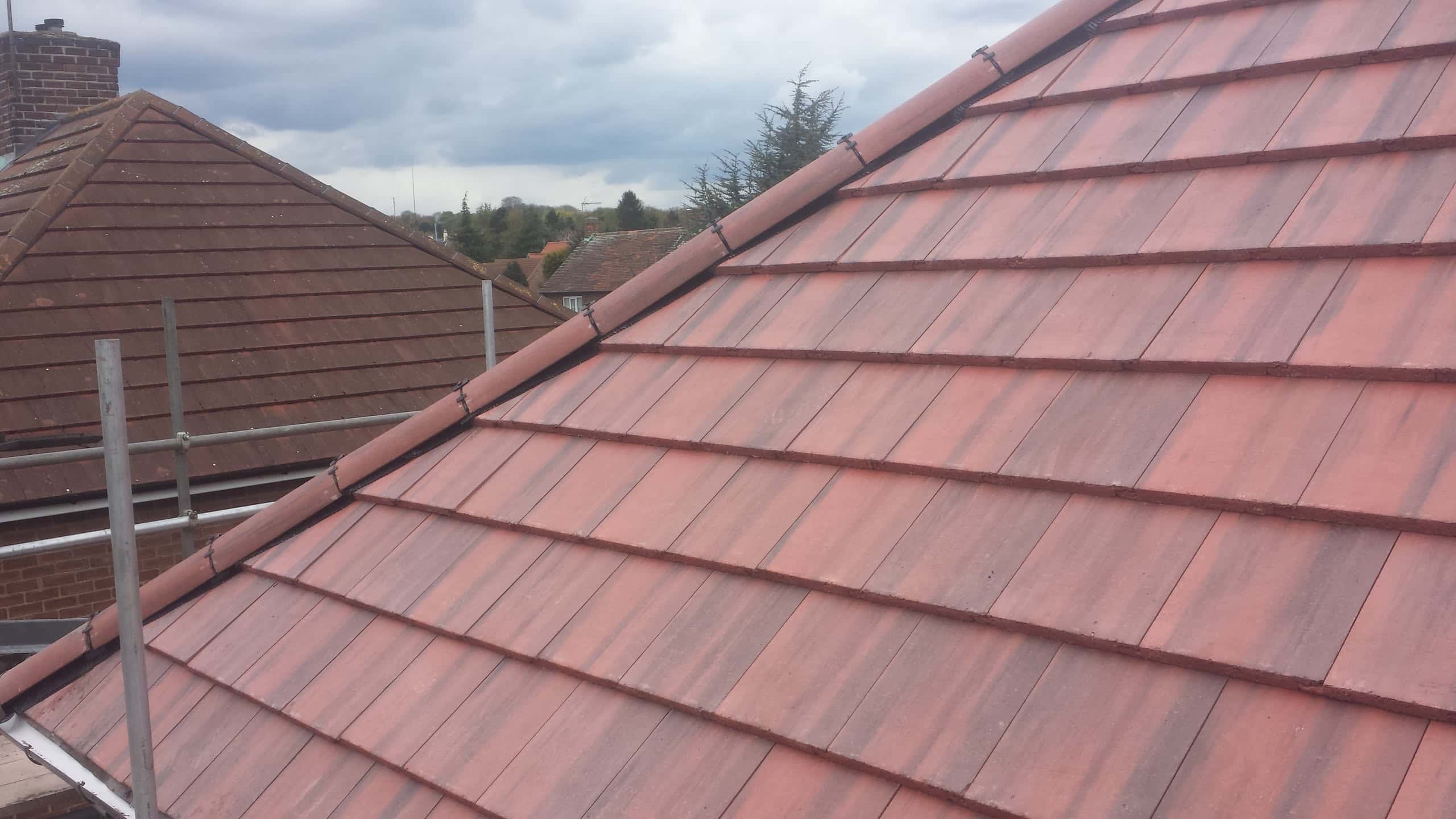 Newly completed pitched roof with red concrete tiles and ridge tiles