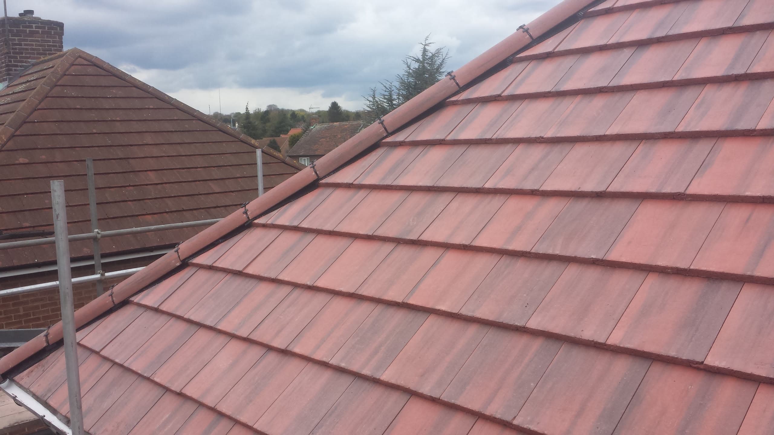 Newly completed pitched roof with red concrete tiles and ridge tiles