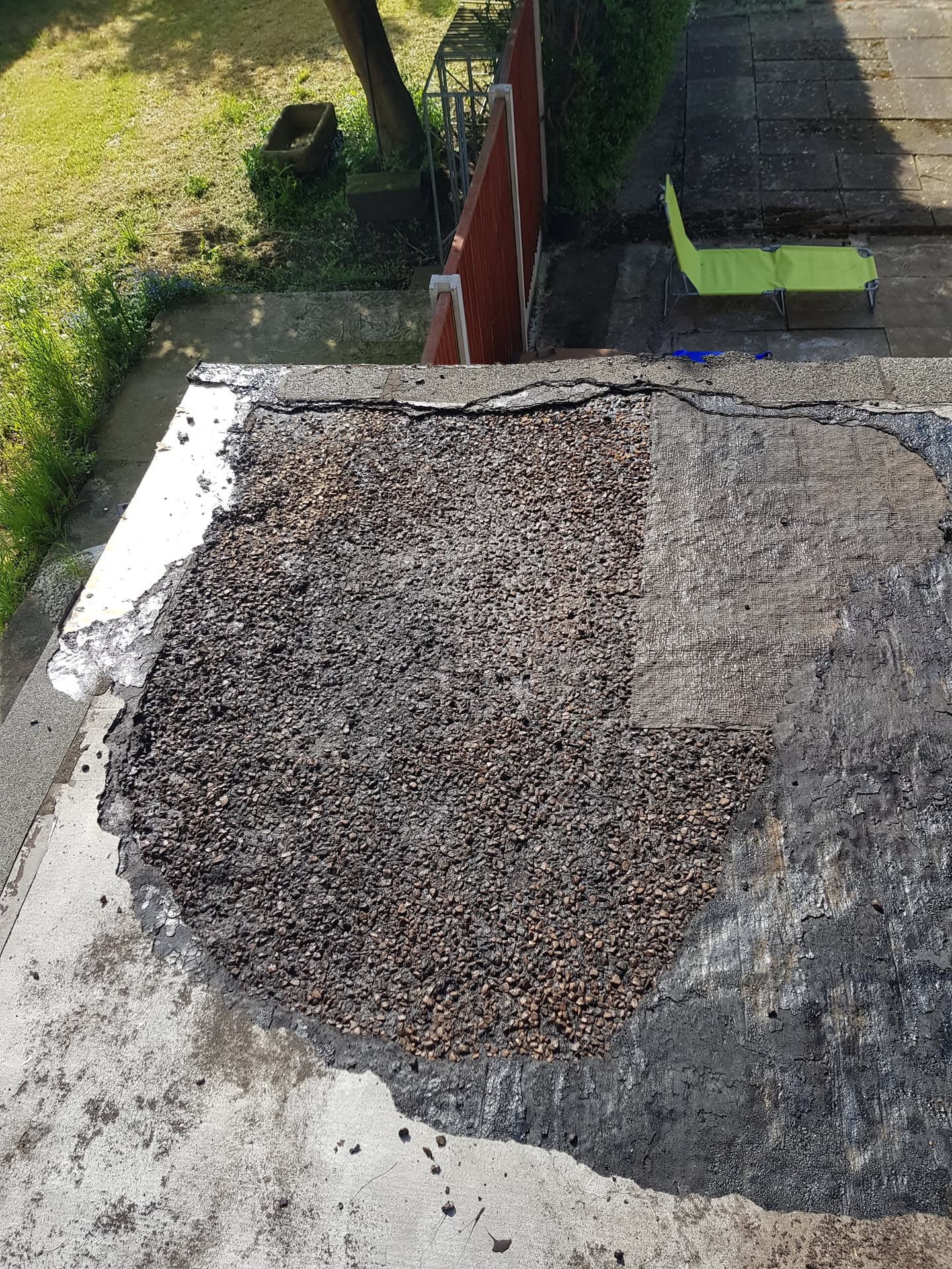 Flat roof with gravel surface and exposed felt underlayer during repair work