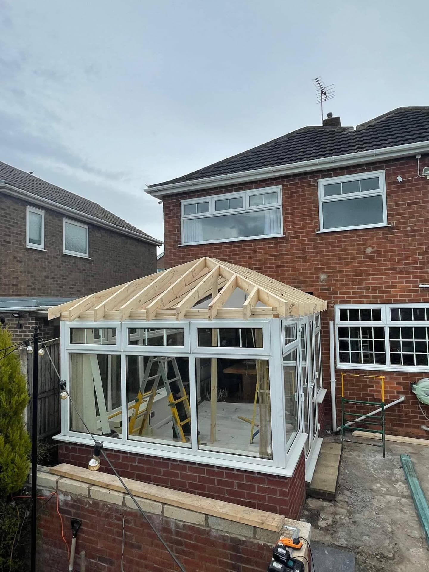 Conservatory with new timber roof frame under construction on red brick house