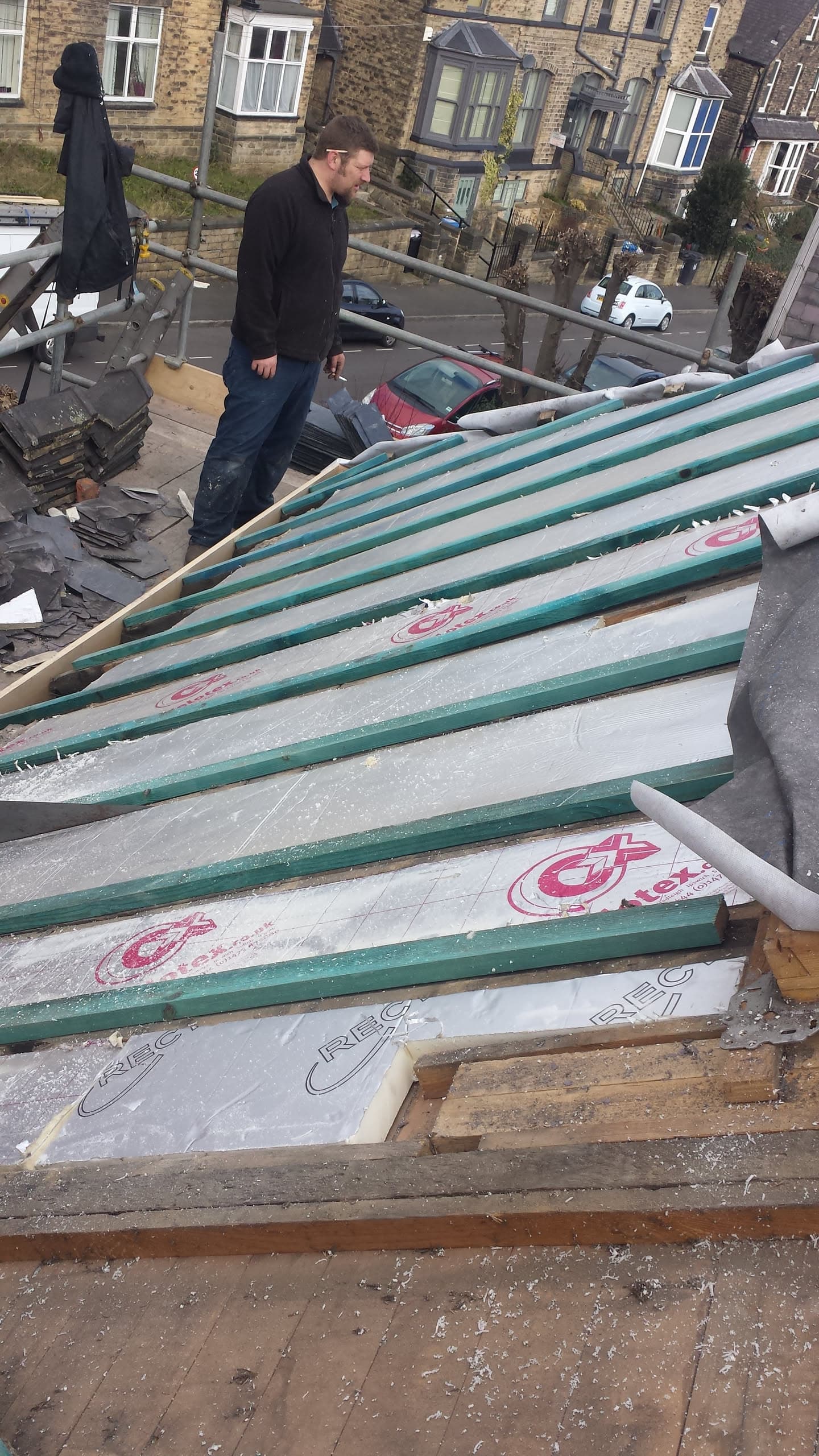 Fitter installing insulation boards with green battens on flat roof