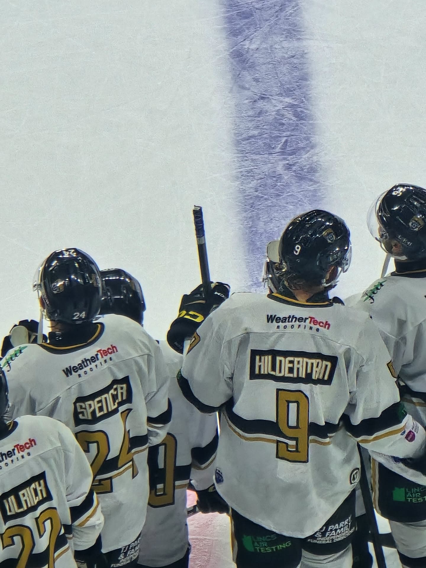 Ice hockey players wearing WeatherTech Roofing sponsored jerseys on the ice
