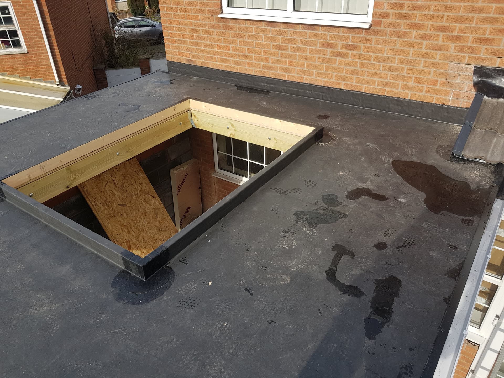 Flat roof with timber-framed skylight opening under construction on residential extension