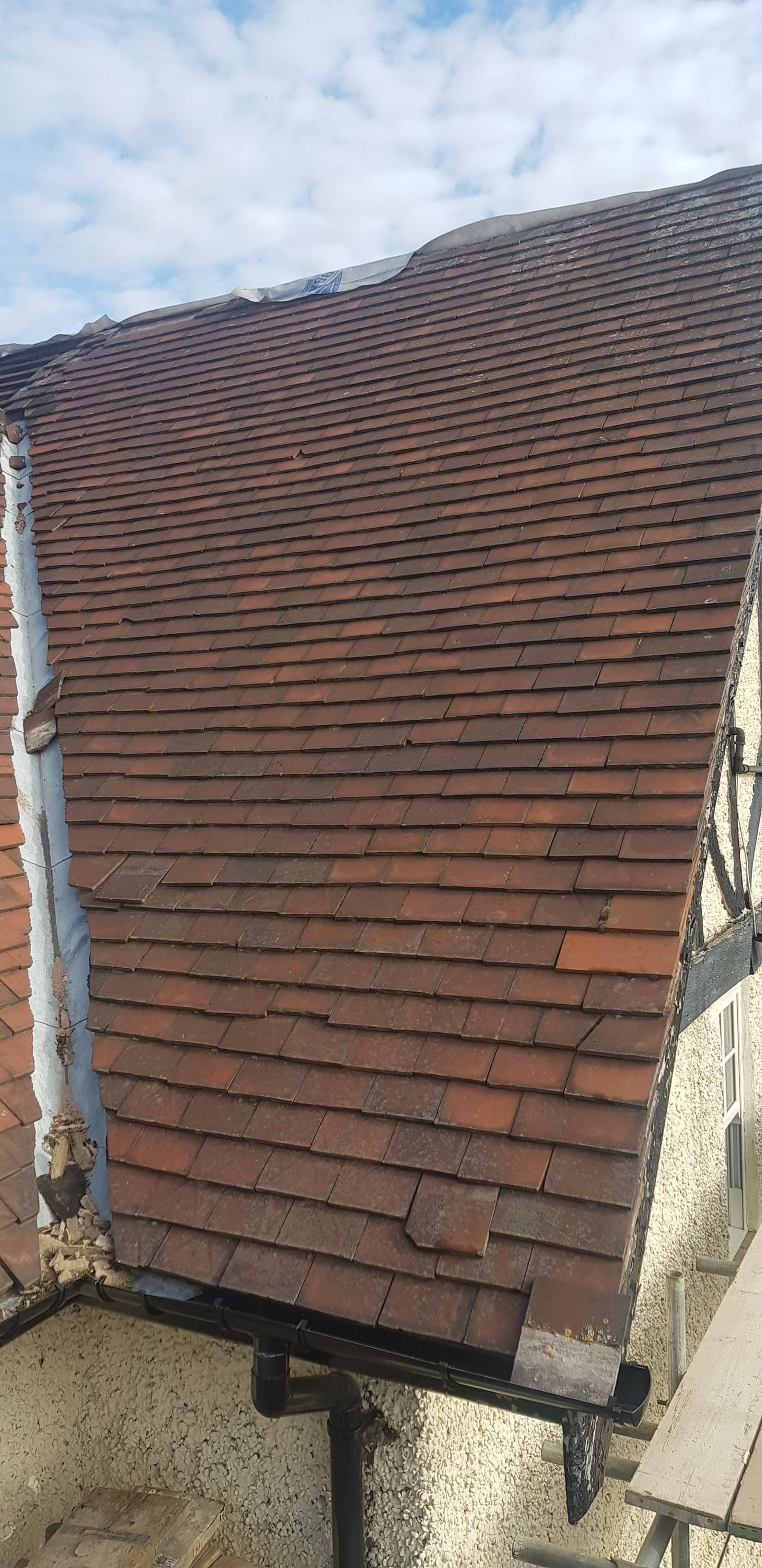 Pitched roof with red-brown concrete tiles and black guttering