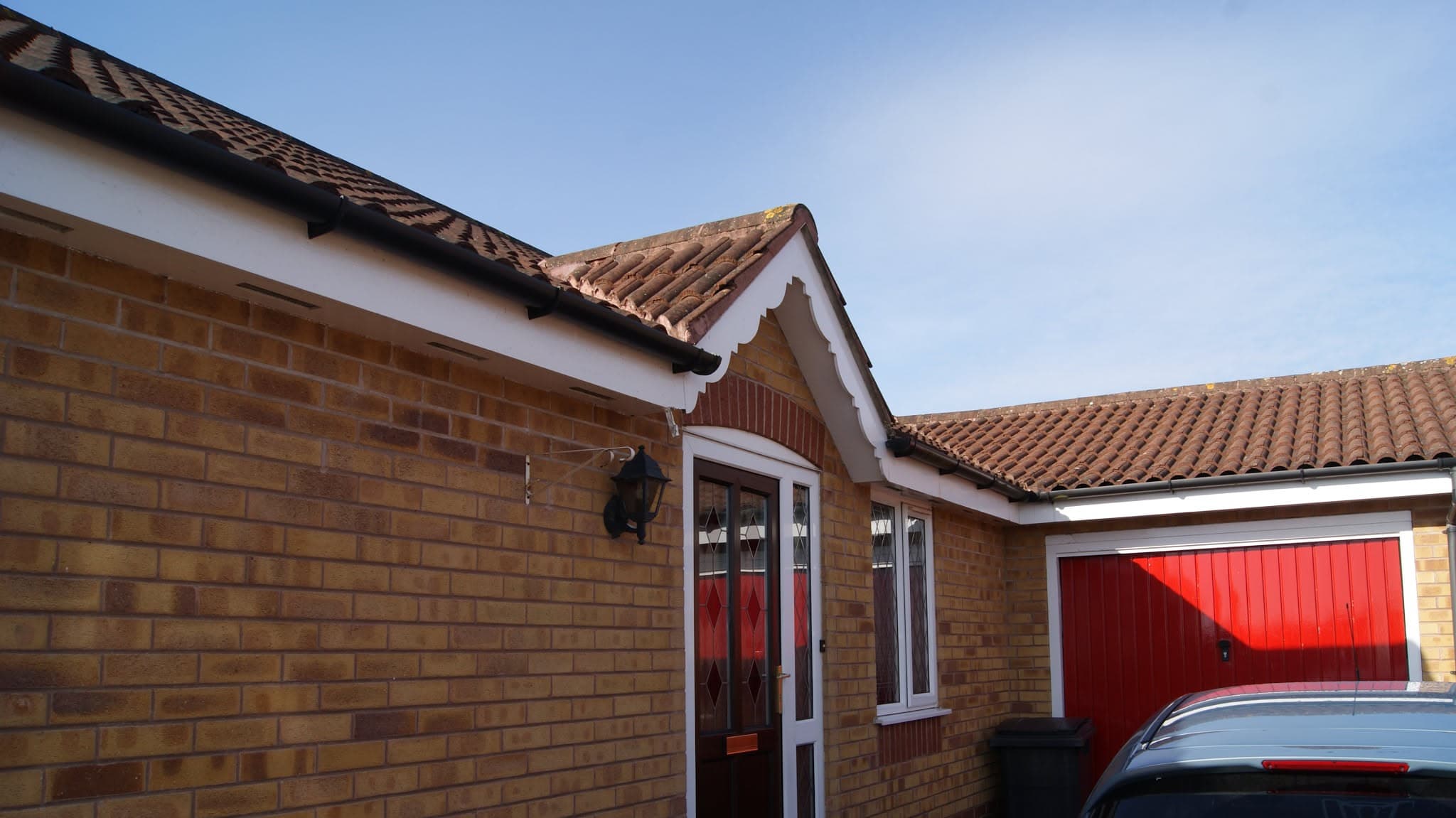 Pitched roof with terracotta clay tiles and white fascias on brick bungalow