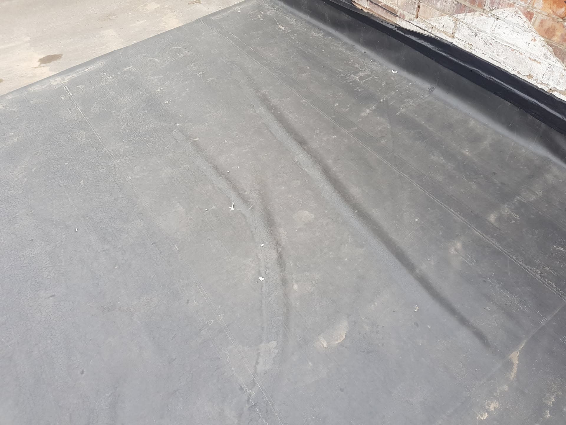 Completed flat roof installation with grey EPDM rubber membrane and black edge trim