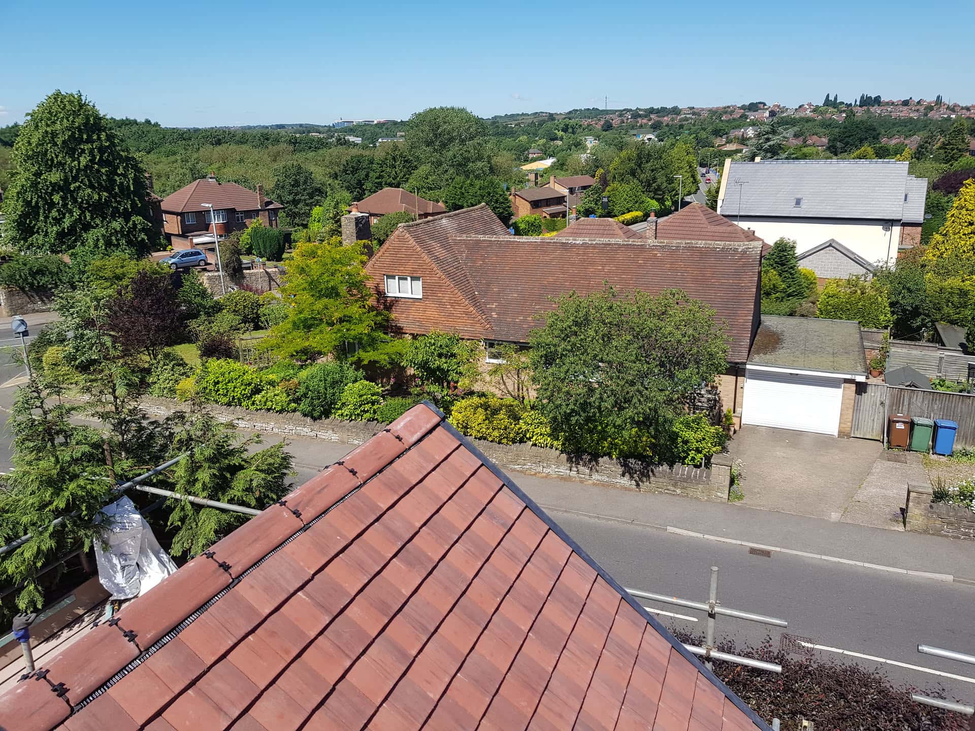 Newly completed pitched roof with red clay tiles and ridge vents on residential property