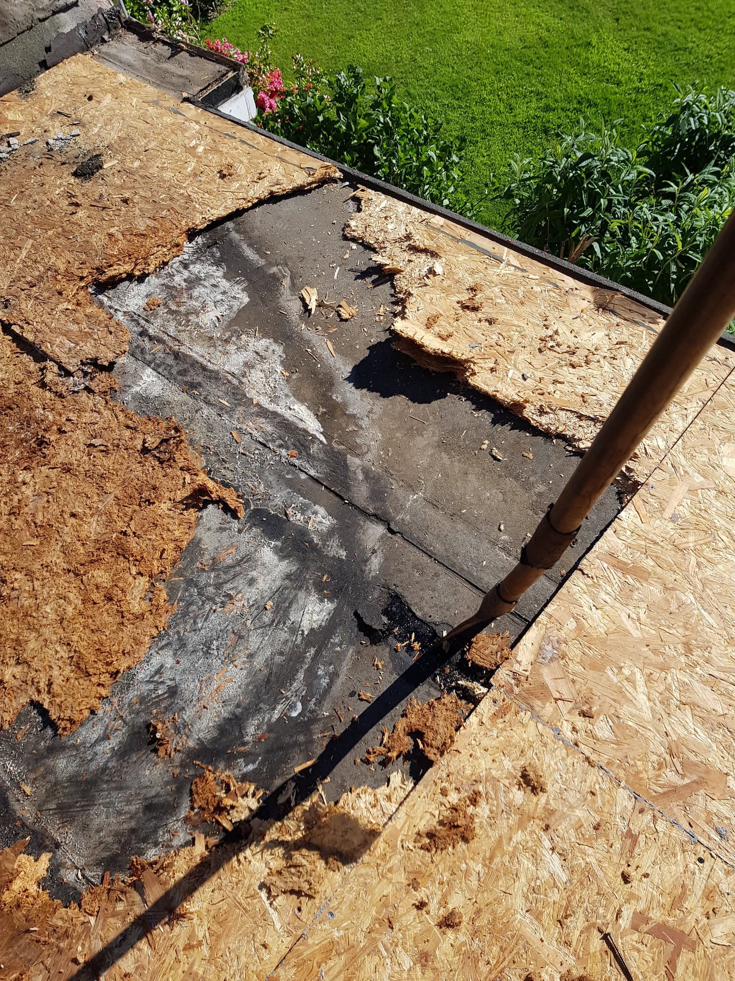 Flat roof with damaged felt being stripped back to OSB decking during repair work