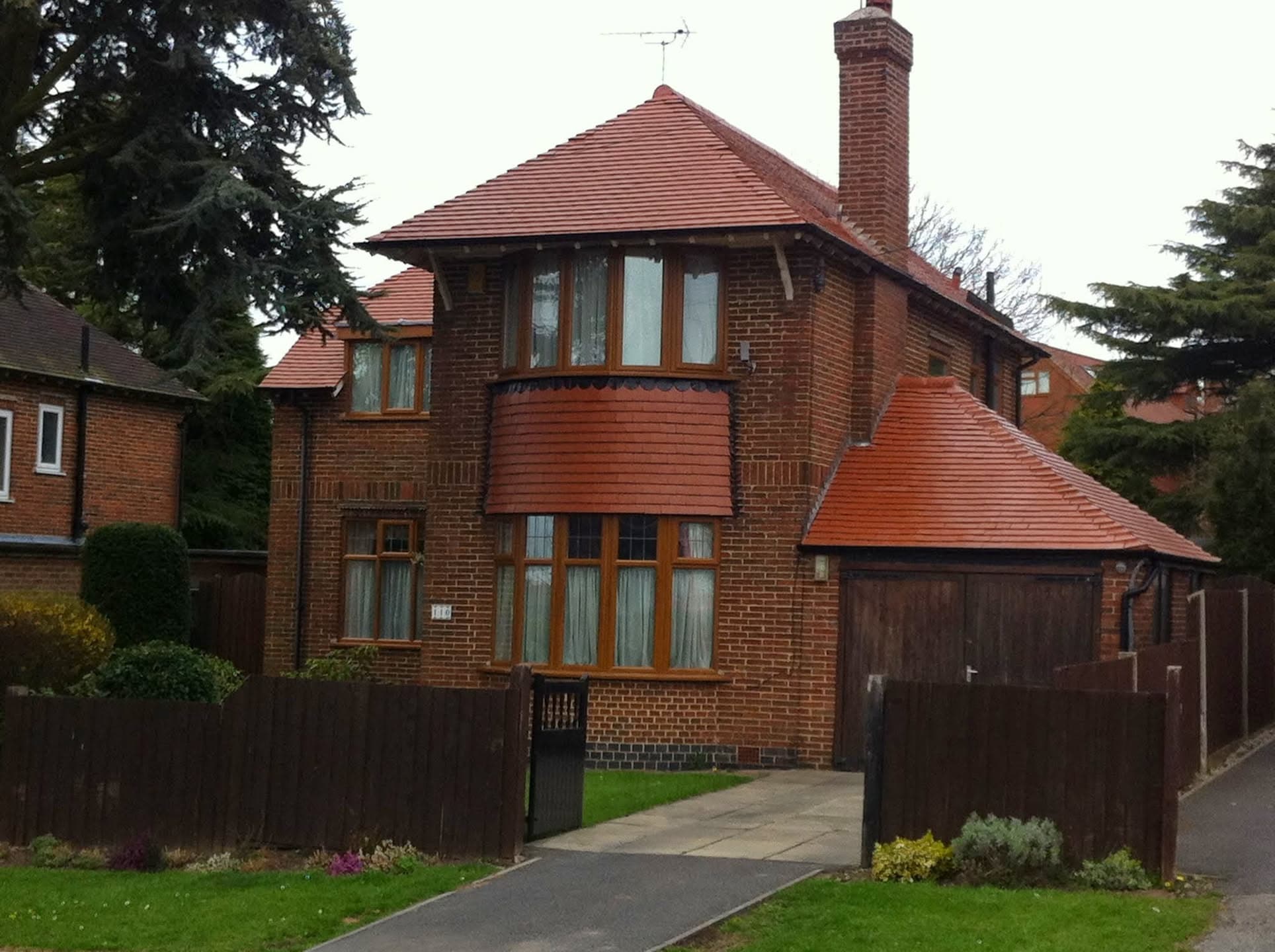 Red clay tiled pitched roof on brick house with tall chimney stack