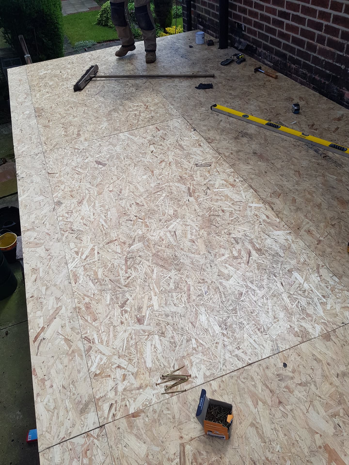 OSB boarding installed on flat roof with tools and fitter's feet visible