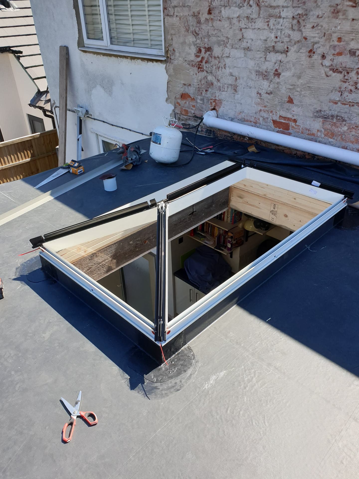 Flat roof with dark grey felt membrane and open roof lantern with timber frame