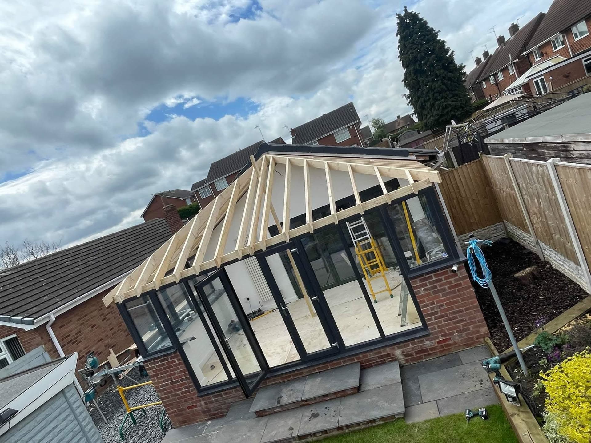 Conservatory roof under construction with exposed timber frame and black glazing bars