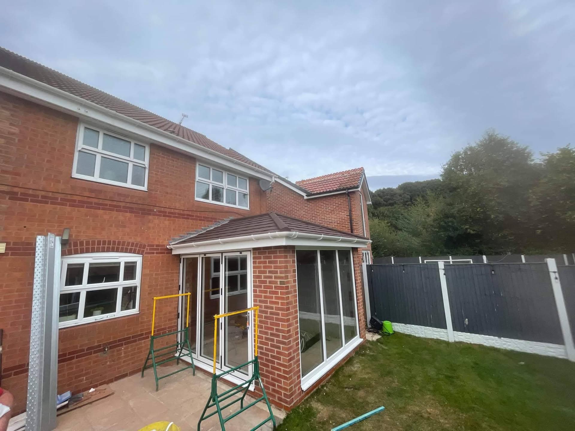 Pitched tiled roof on brick house extension with brown concrete tiles and white fascias