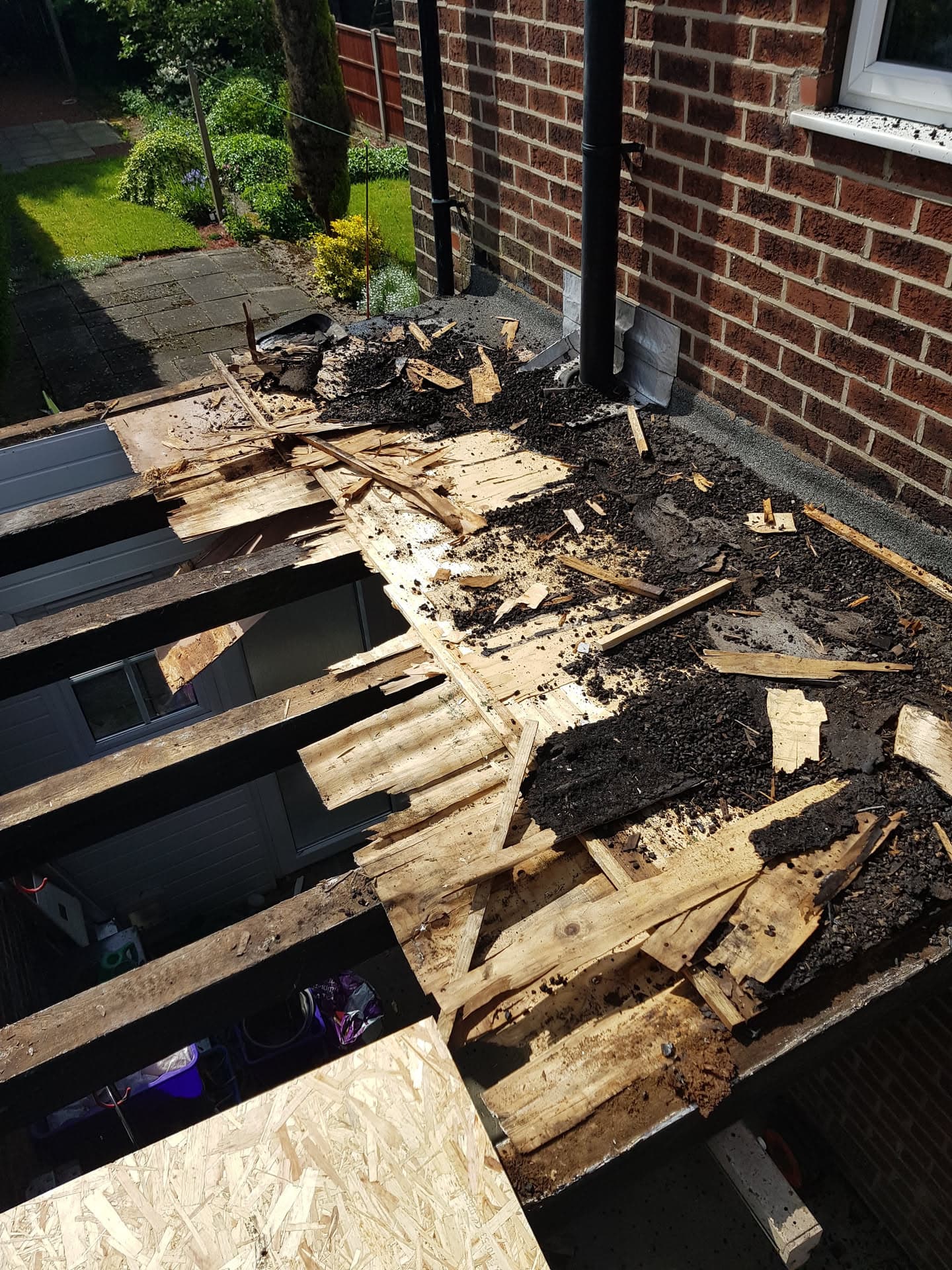 Flat roof stripped back to timber joists showing old felt and decking removed during replacement