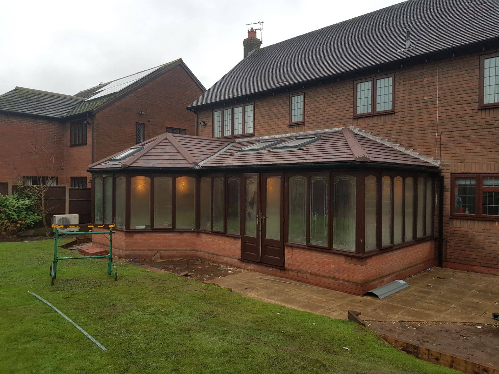 Conservatory with brown tiled roof and roof windows attached to brick house