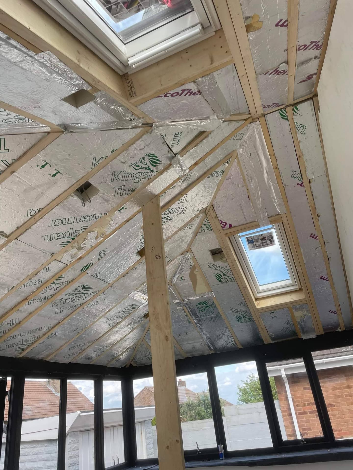 Interior view of pitched conservatory roof with timber frame, insulation and two roof windows during construction