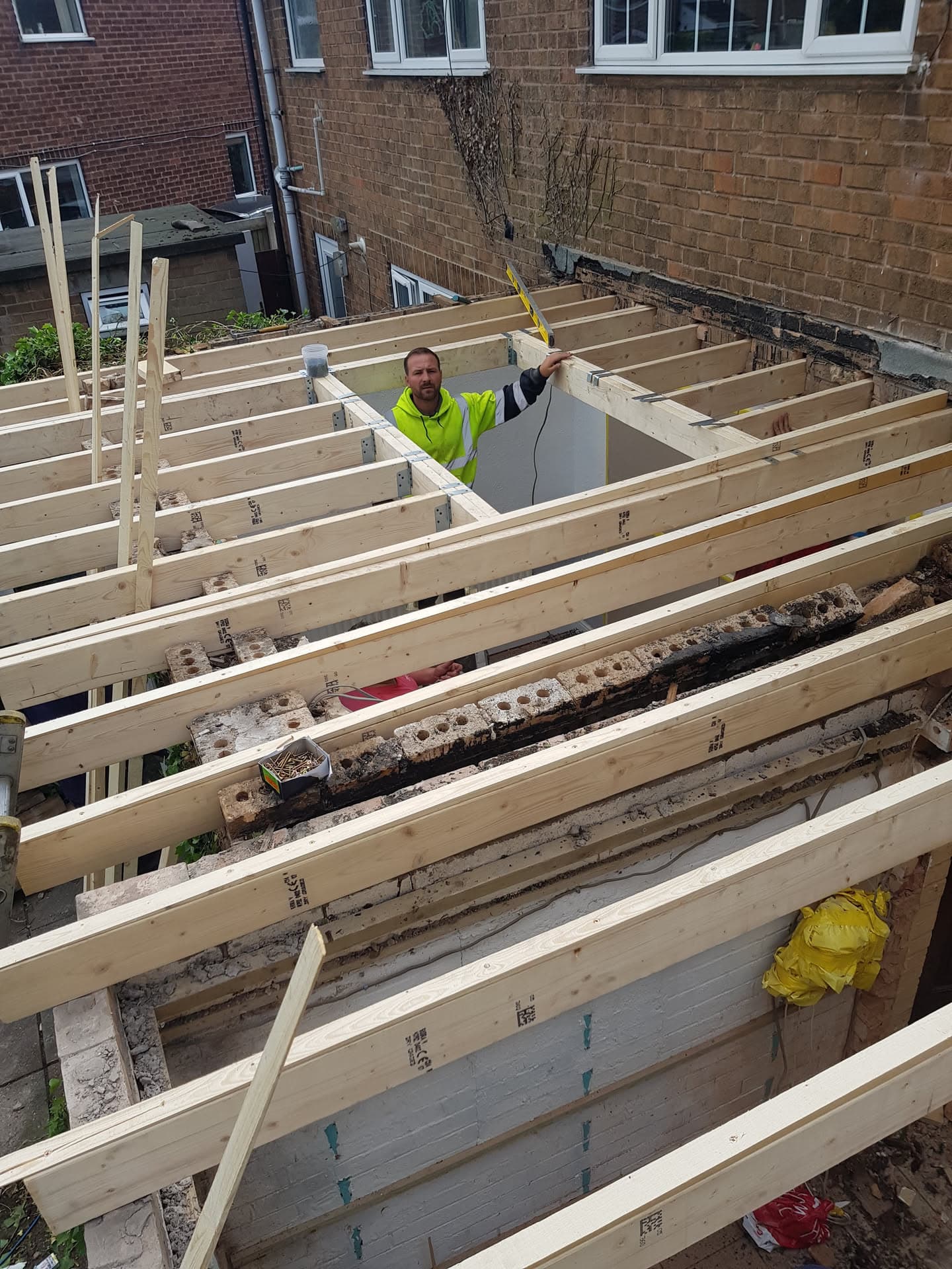 Fitter installing timber joists for new flat roof extension construction