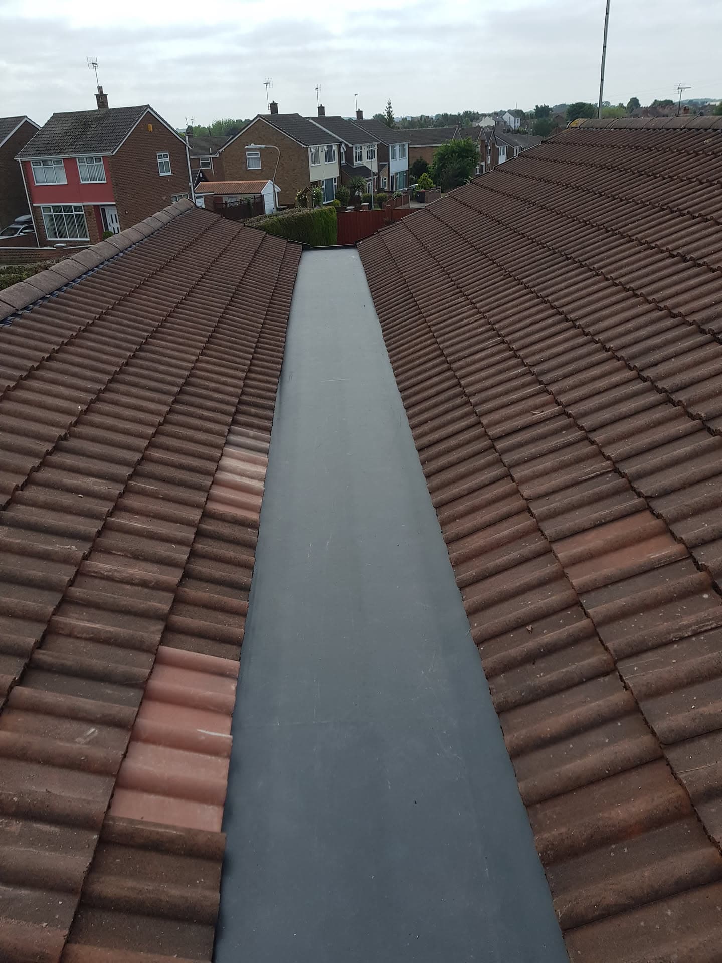 Pitched roof with brown concrete tiles and grey GRP valley gutter