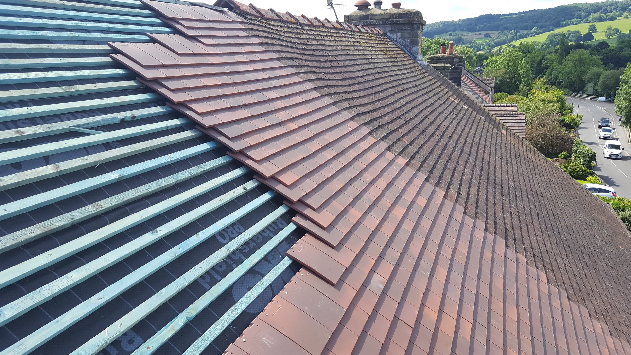 Pitched roof with brown concrete tiles and metal roofing battens, chimney stack visible