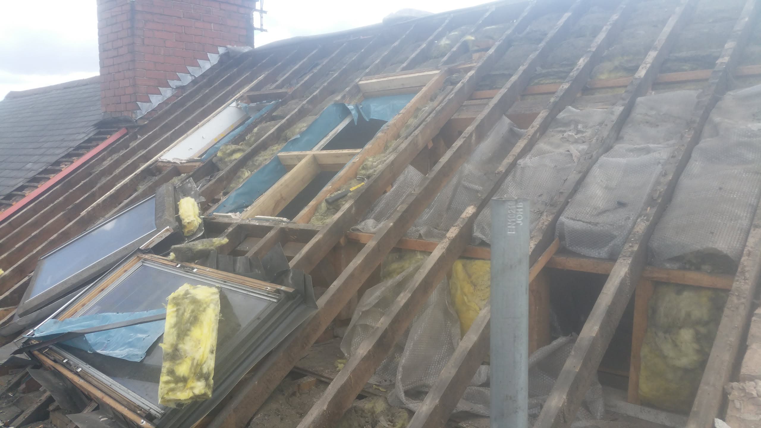 Pitched roof with exposed timber battens, insulation and roof windows during re-roofing work